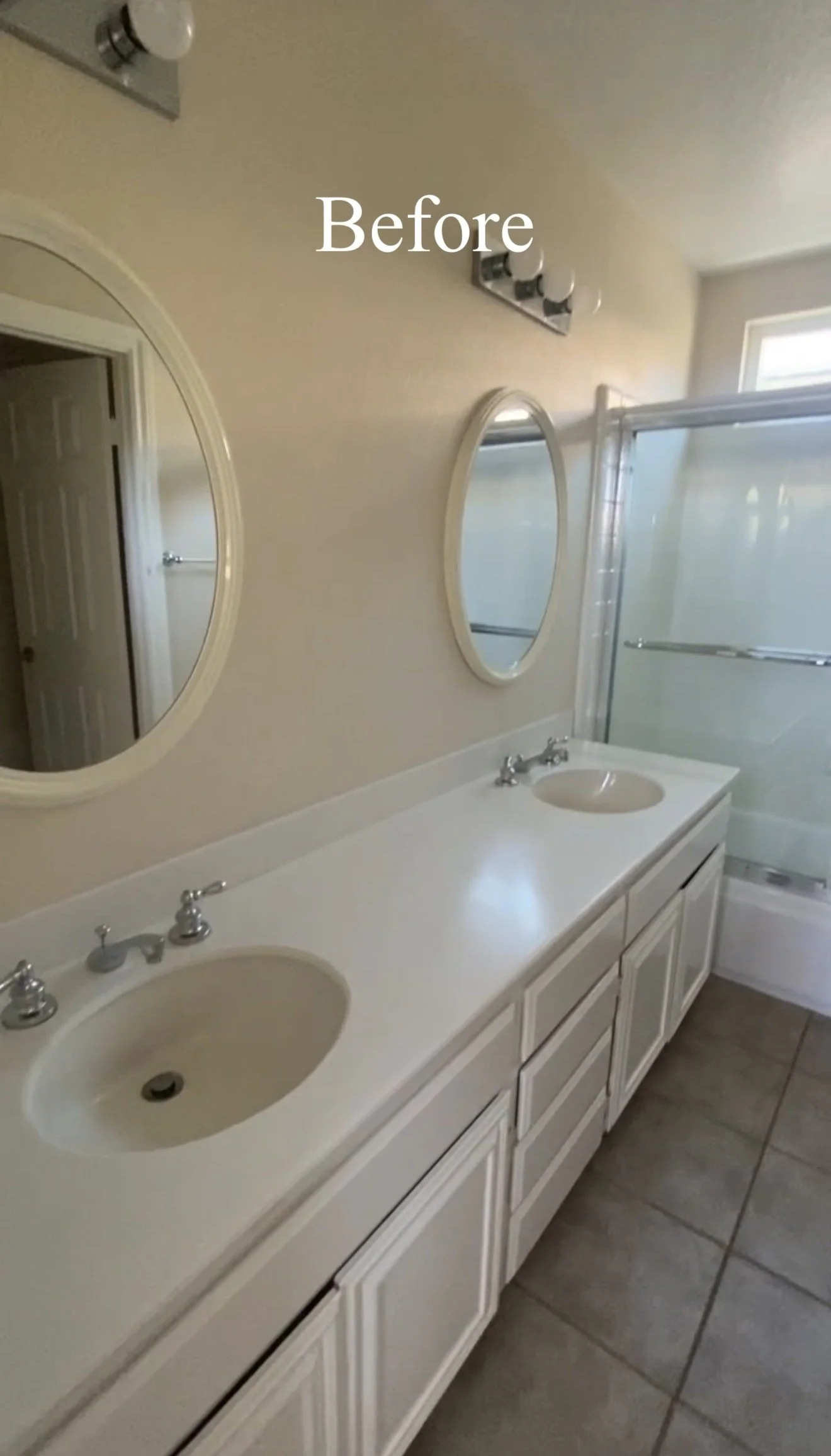 Bathroom with double sink vanity, oval mirrors, shower with sliding door, beige walls, and tiled floor, labeled 'Before'.