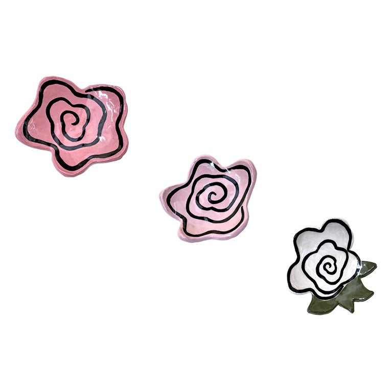 Three decorative ceramic roses, one pink with black outline, another pink with black outline, and one white with black outline, with green leaves