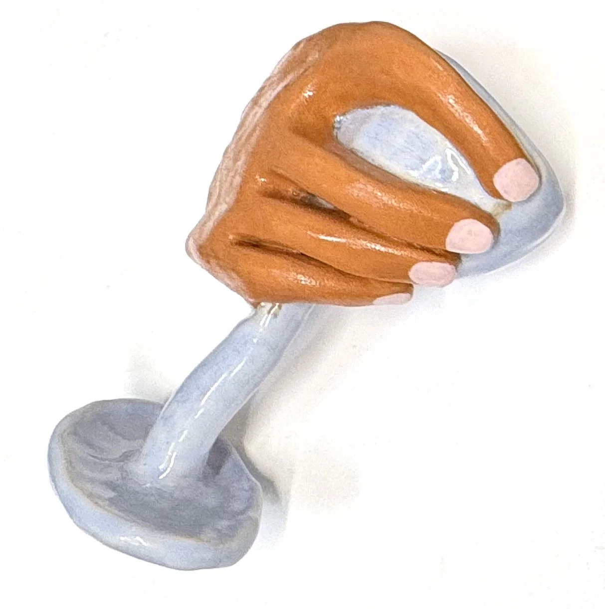 A light blue ceramic glass, held in a hand with pink painted nails.