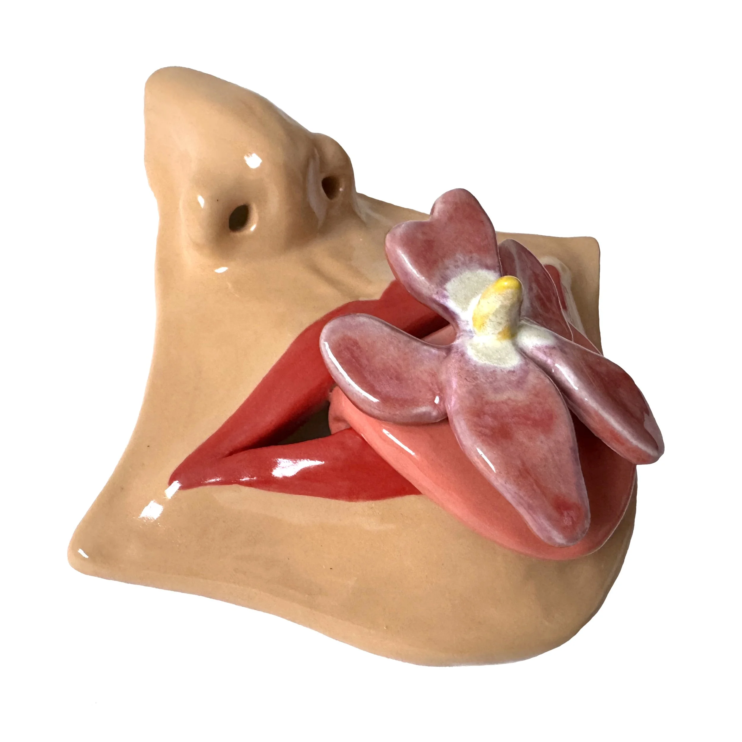 Ceramic human face sculpture with open mouth and pink flower resting on lips.