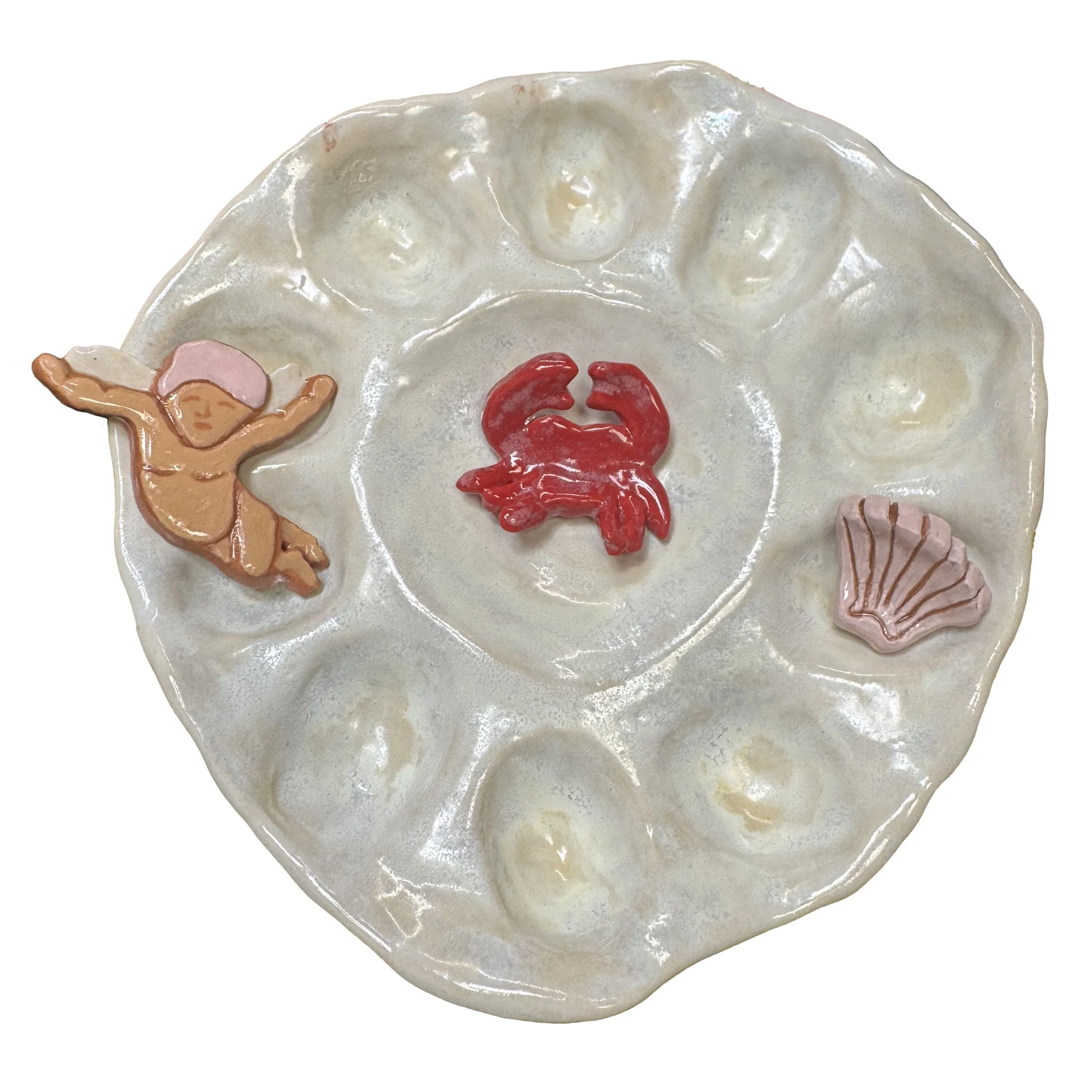 A ceramic divided dish with a crab in the center, a cherub on the left, and a seashell on the right.