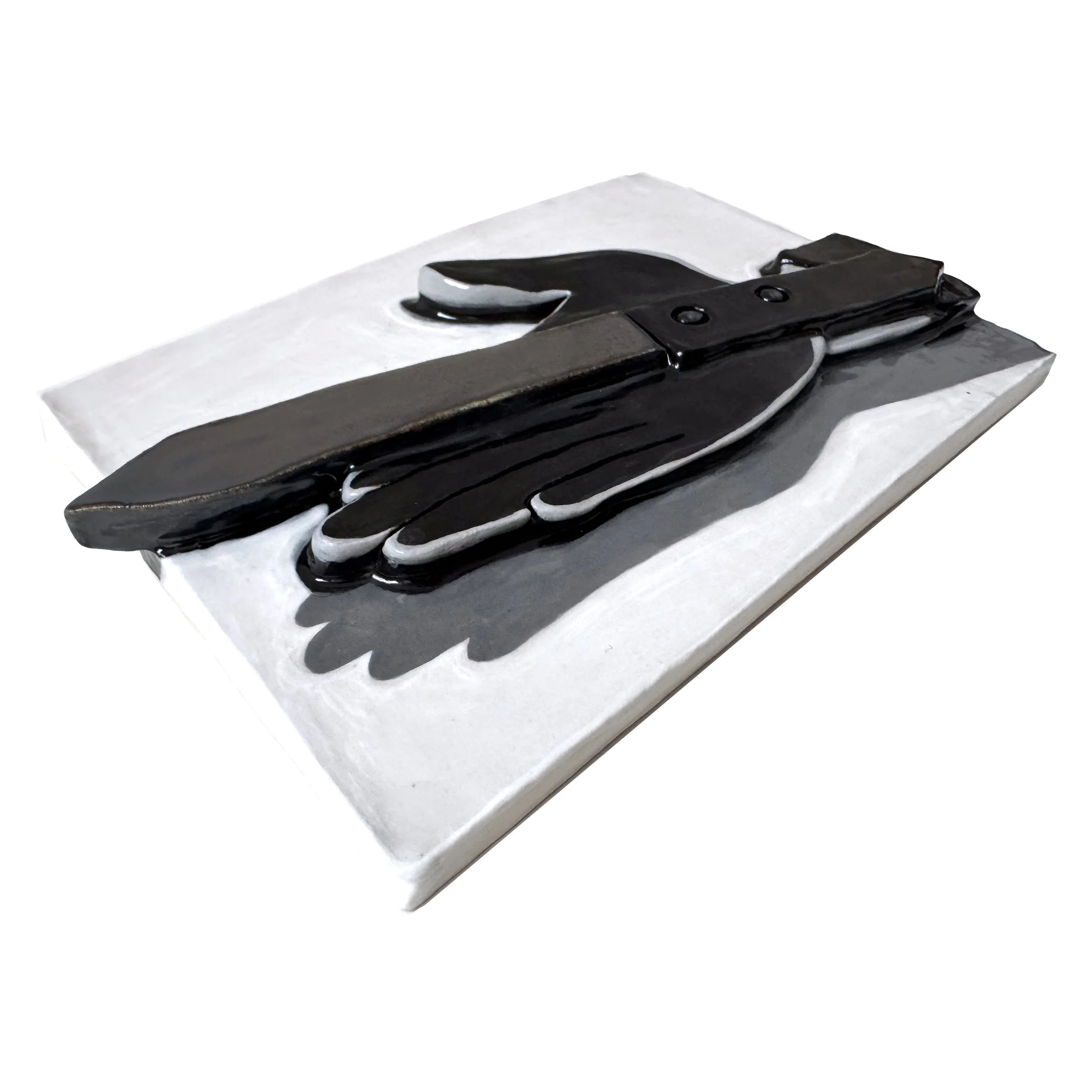 Side view of a black and white ceramic relief depicting a knife resting across a shadowy hand.