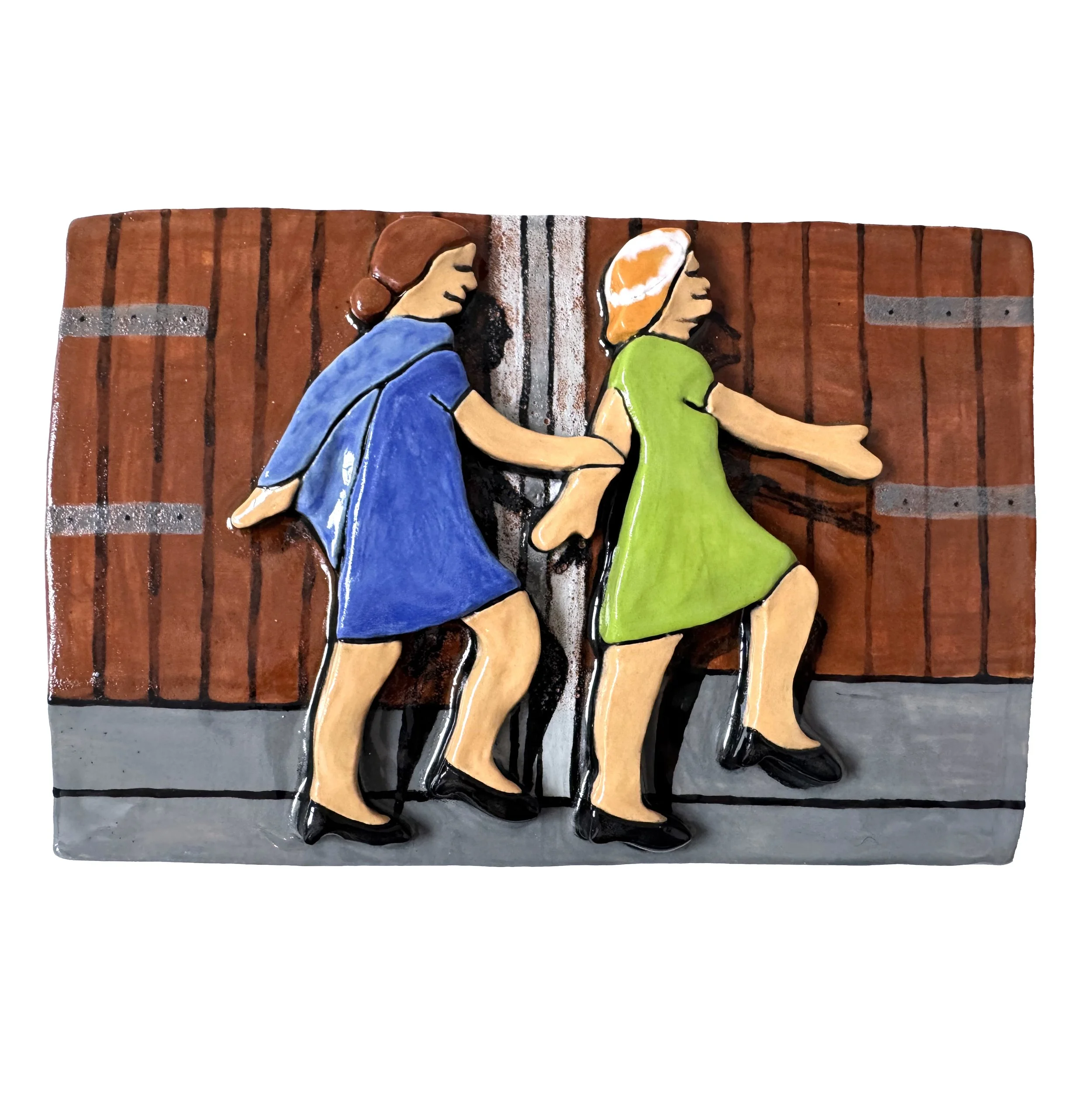 Colorful ceramic tile of two women in dresses, one blue and one green, appearing to be in a dancing or playful pose against a wooden fence background.