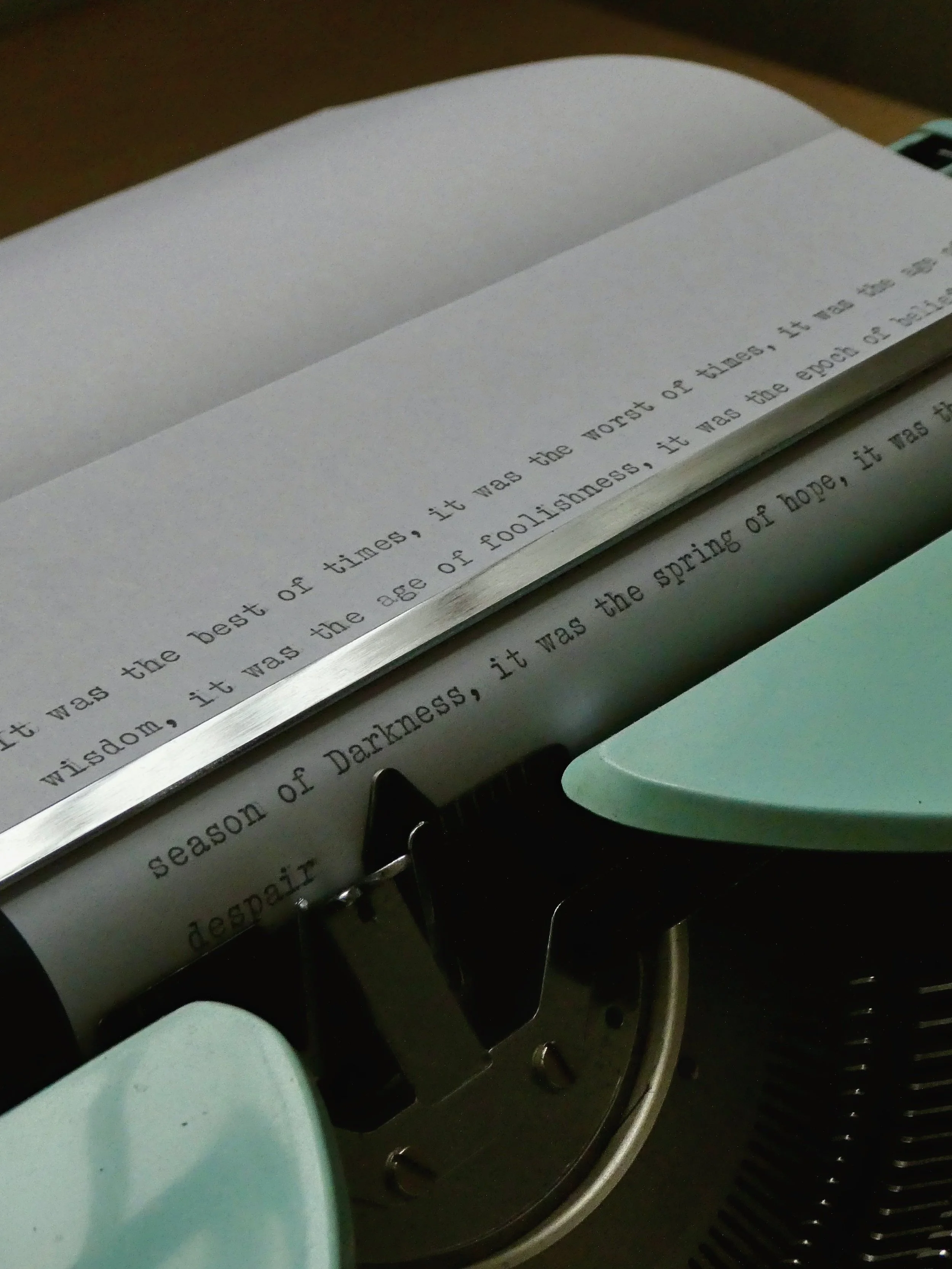 Close up of teal typewriter writing: "It was the best of times, it was the worst of times".