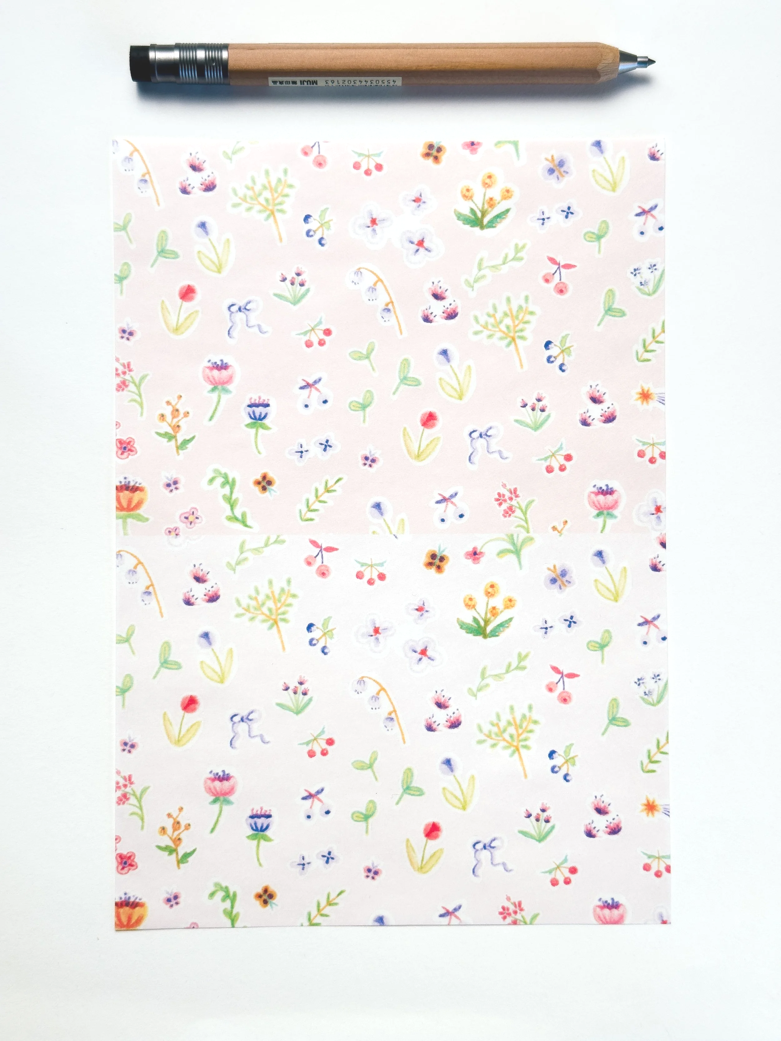 Colored floral patterned paper with small flowers and leaves, and a wooden ballpoint pen on a white background.