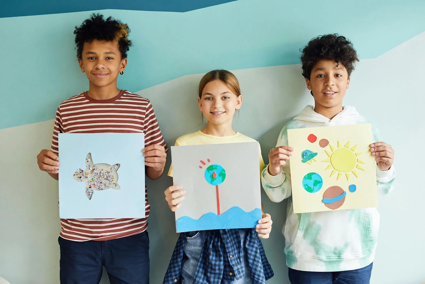 Smiling group of proud children presenting nature inspired art projects.
