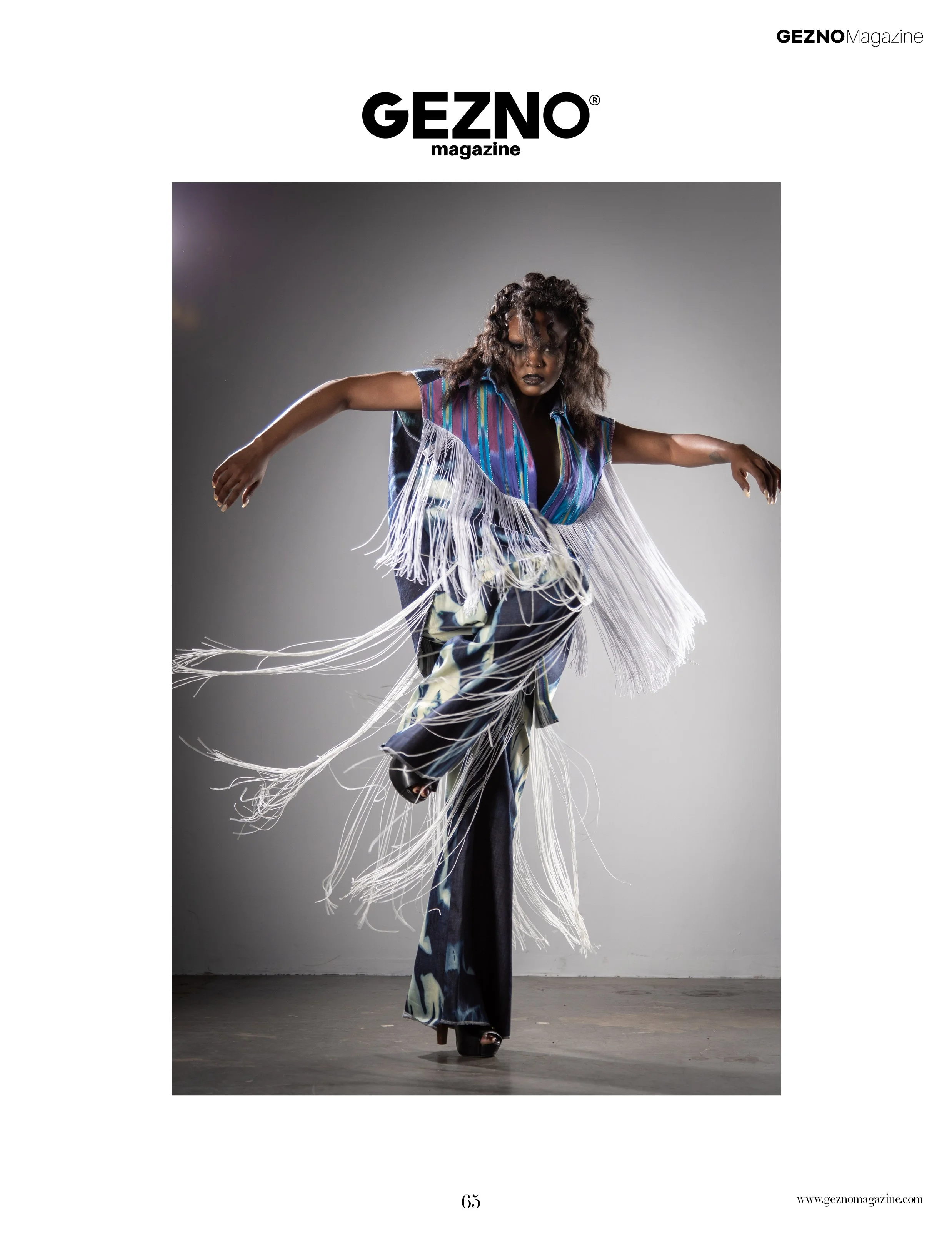 A person dancing or performing in an artistic pose wearing a colorful fringed outfit with black open-toed heels, set against a plain background with professional lighting.