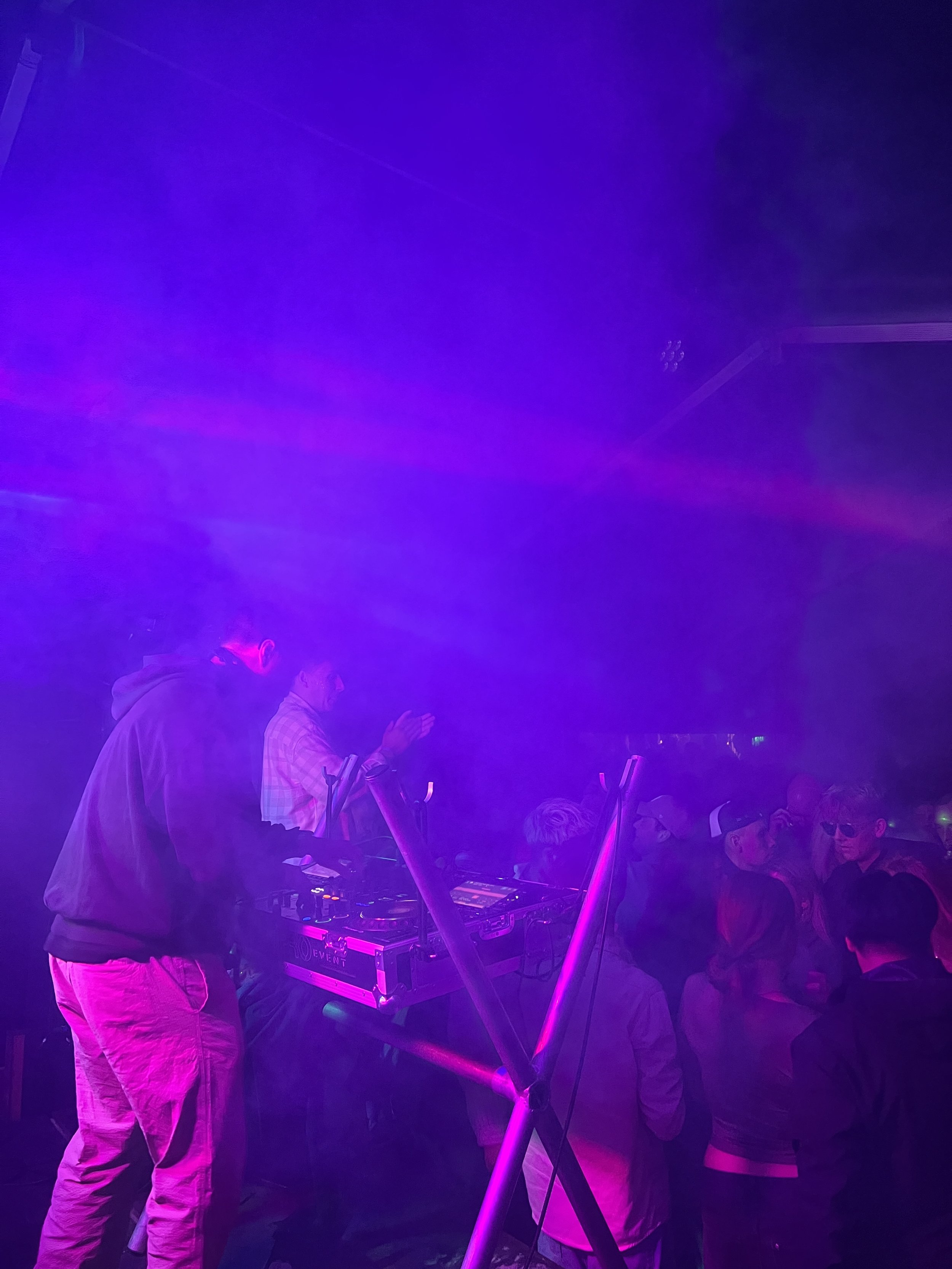 Dansende mennesker i en nattklub med lyseffekter og en DJ.