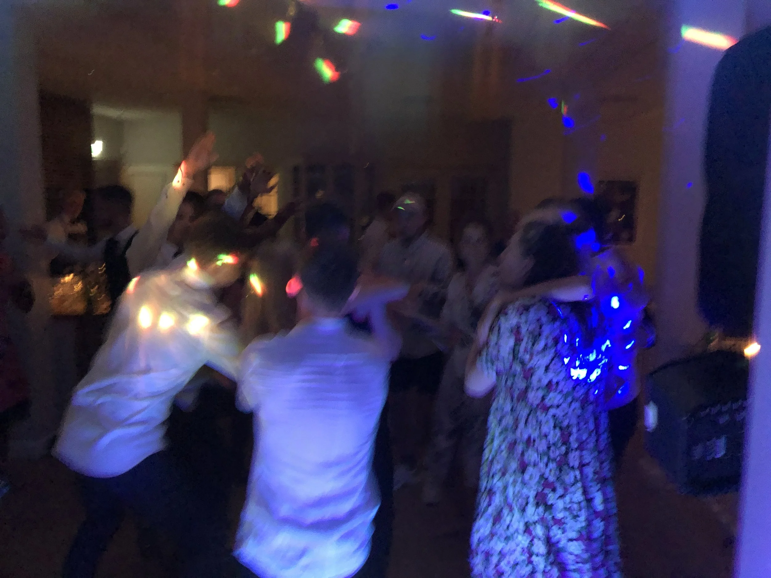 Dansende mennesker i et mørkt rum med diskolys, nogle har deres arme i vejret og ser ud til at danse og have det sjovt.