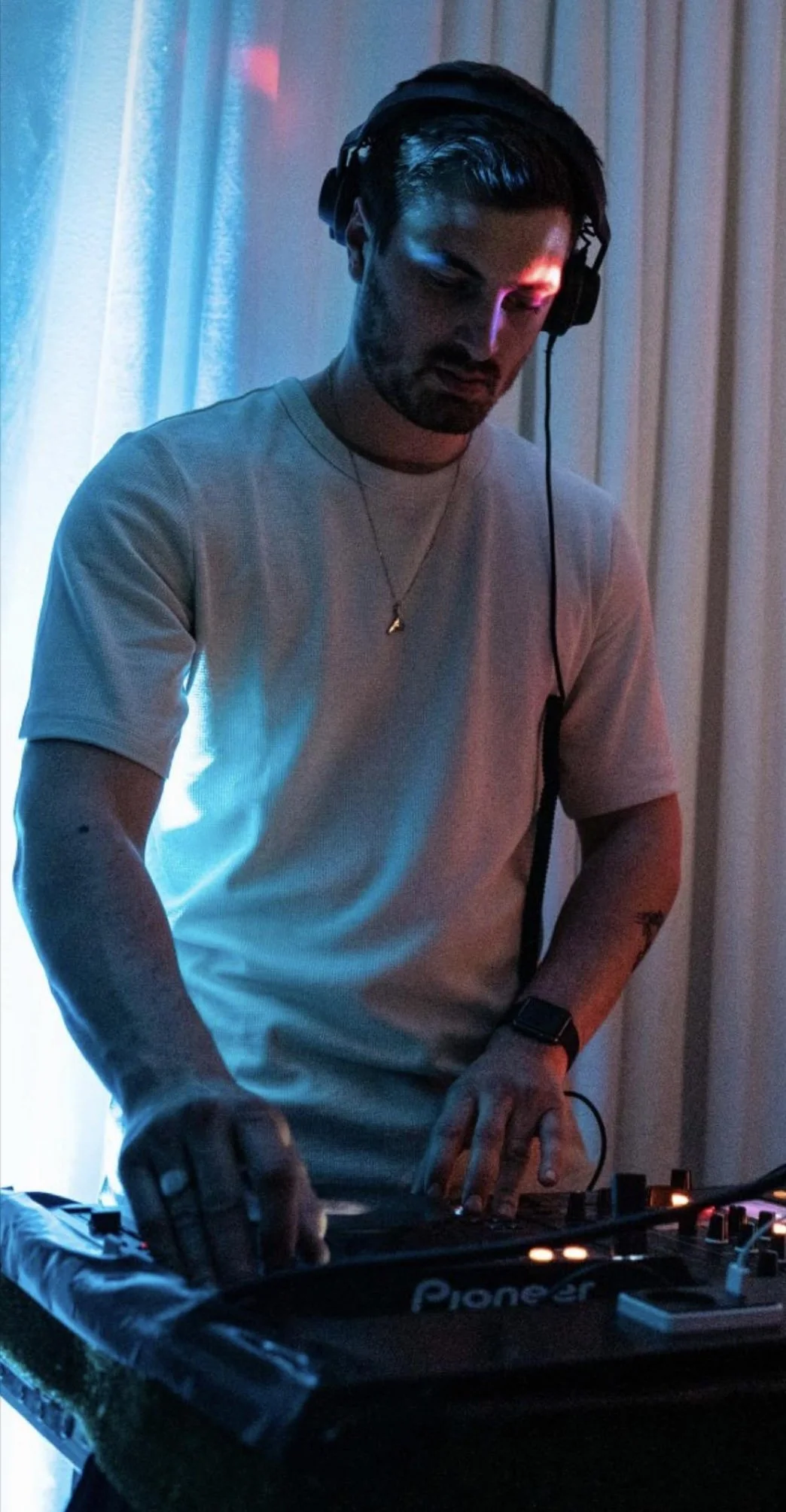 En mand med høretelefoner, der DJ'er ved en mikser.
