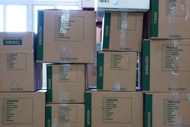 Mehrere Kartons in verschiedenen Größen, die zum Versand bestimmt sind, auf einem Regal gestapelt.