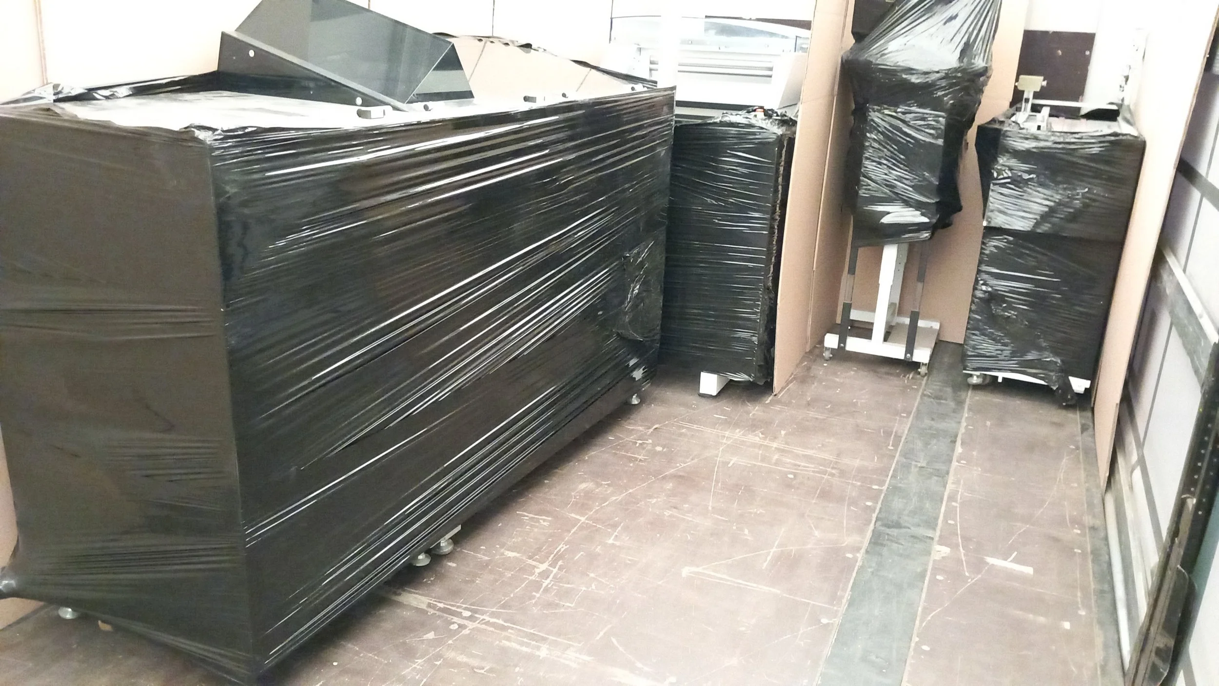 Industrieartige Raum mit schwarz-umwickelten Geräten, wahrscheinlich medizinische oder technologische Ausrüstung, auf Rollen