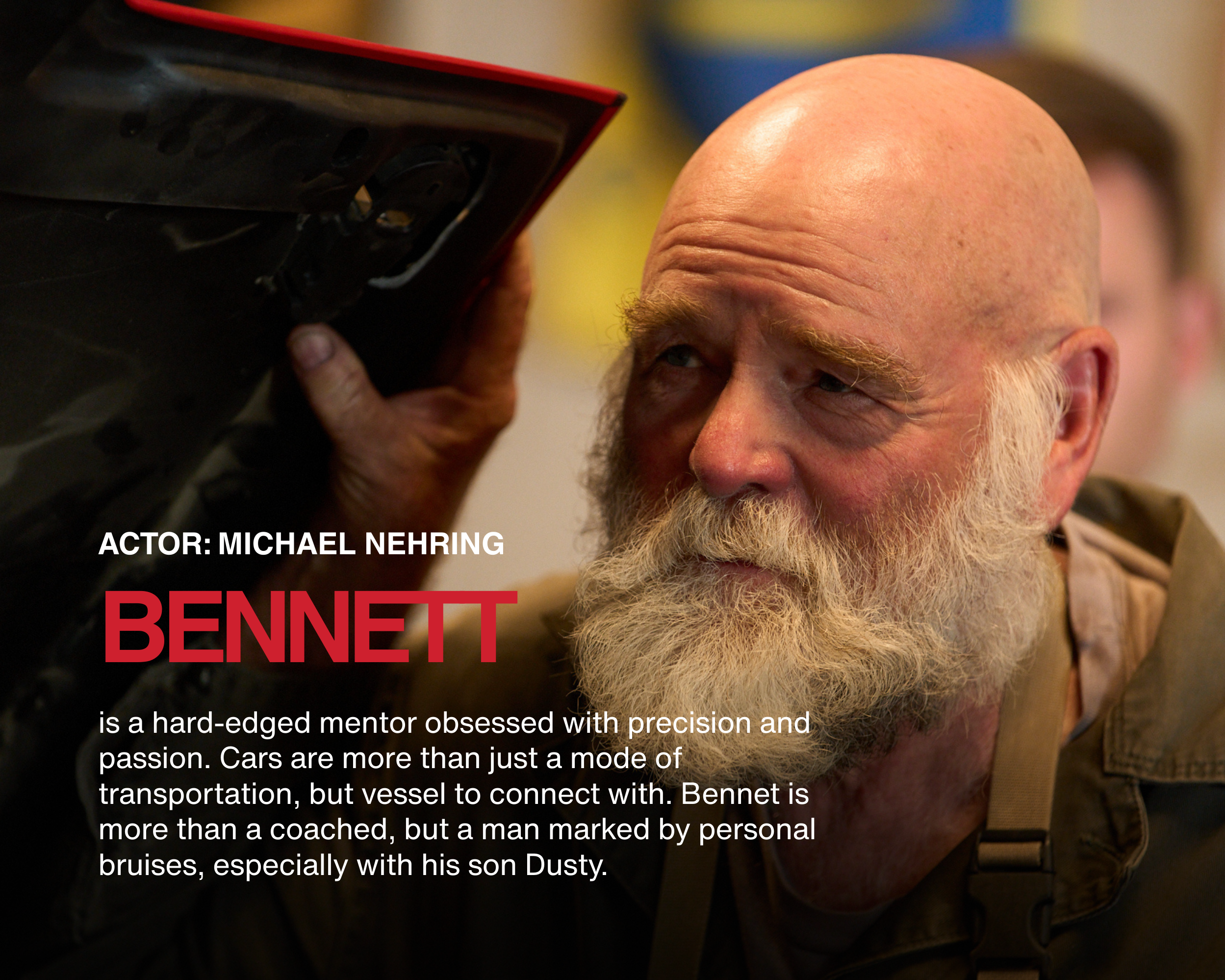 Close-up of a man with a white beard and bald head, looking intently at a black object held in his hand.