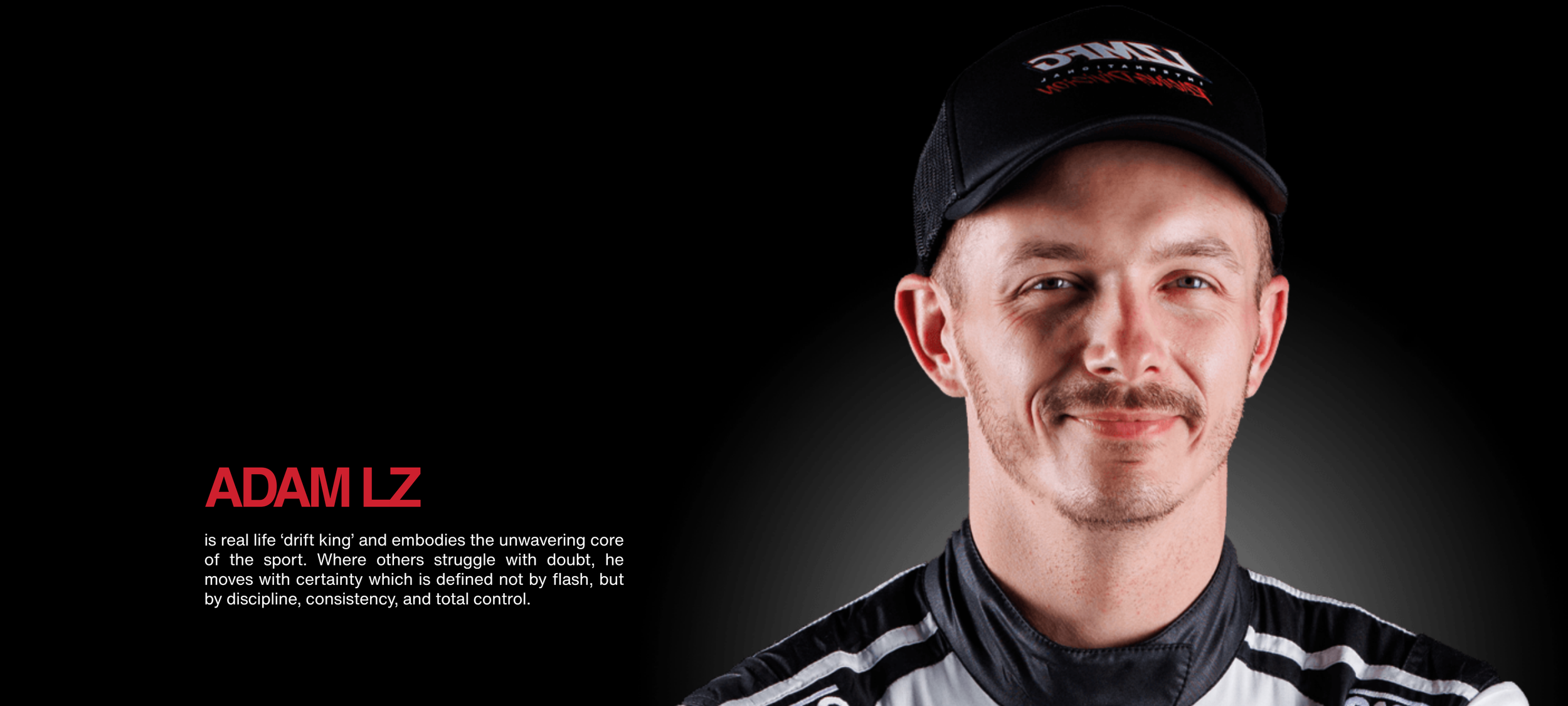 A portrait of Adam Lz wearing a black and white racing suit and a black cap with red and white lettering, smiling at the camera against a dark background.