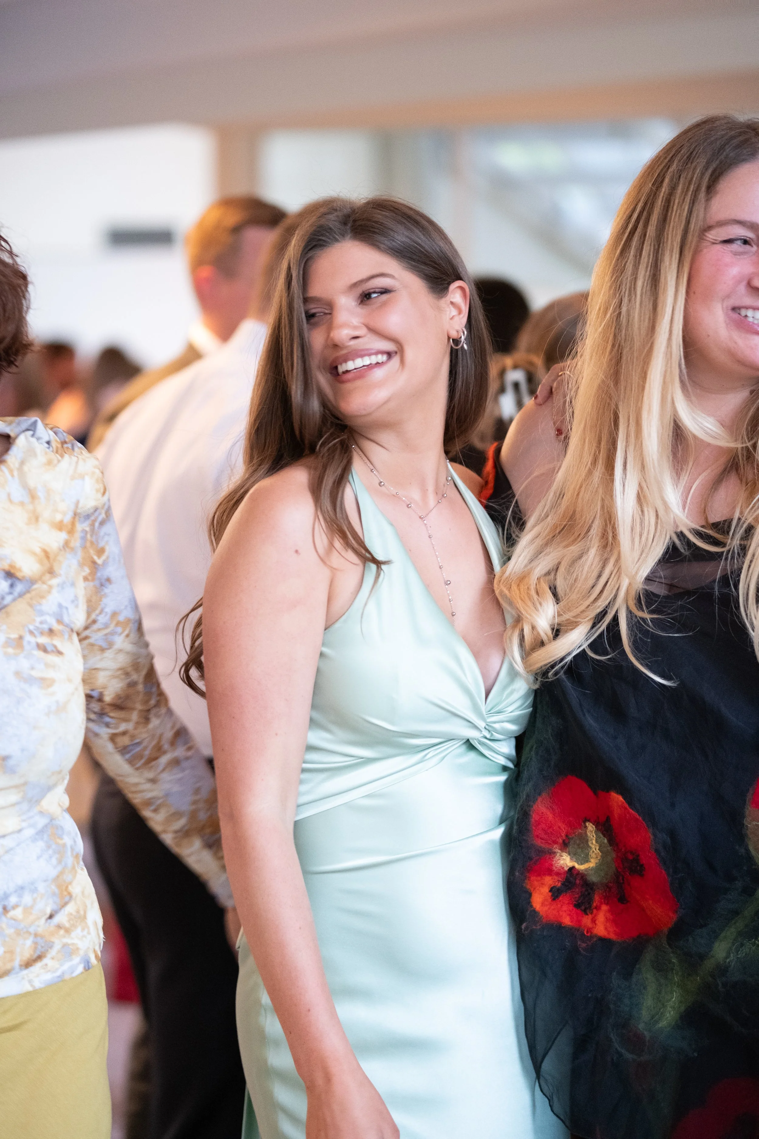 Smiling woman in a light green satin dress at a social event.