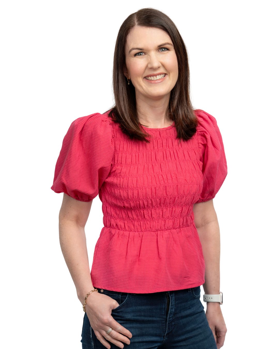 A woman with shoulder-length brown hair, wearing a pink blouse with puffed sleeves and smocked bodice, posing against a solid background, smiling at the camera.