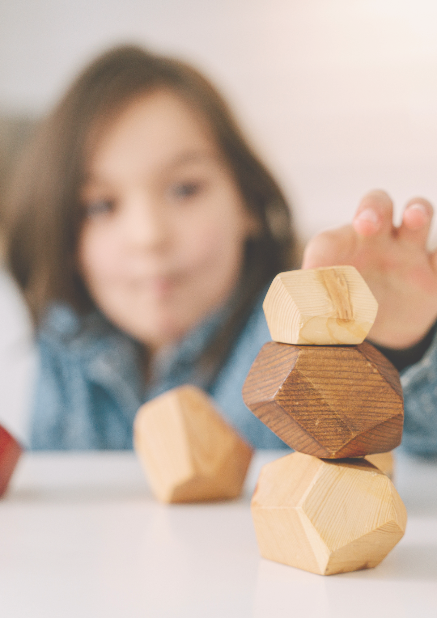 A young woman with brown hair stacked wooden geometric blocks.
