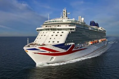 Cruise ship sailing on the ocean with a British flag design painted on its bow.