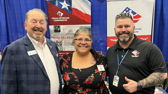 Three people standing in front of Texas Veterans Commission banners, smiling for a photo.