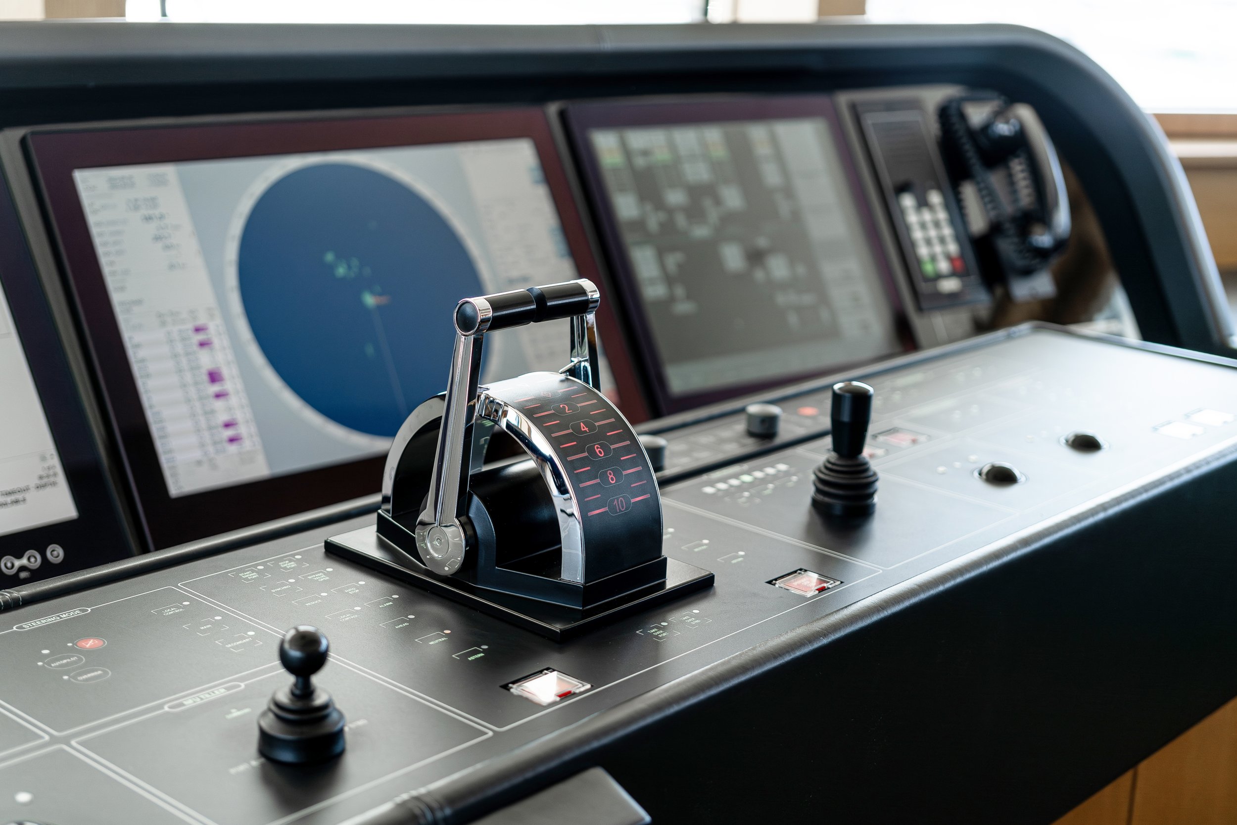 Close-up view of a ship's navigation and control panel with screens, levers, and buttons.