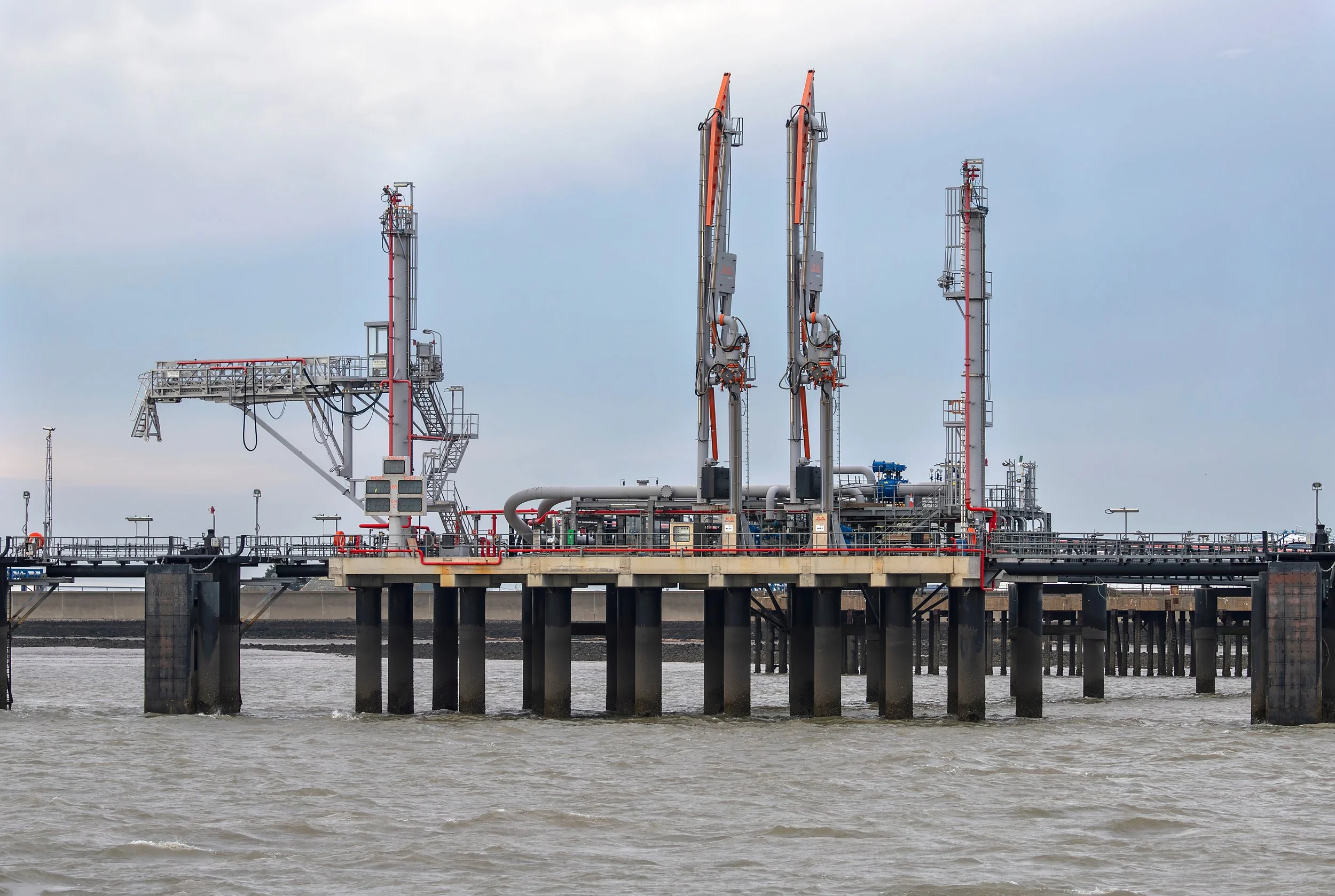 Gas and CO2 loading platform standing on pilings in the water under a cloudy sky.