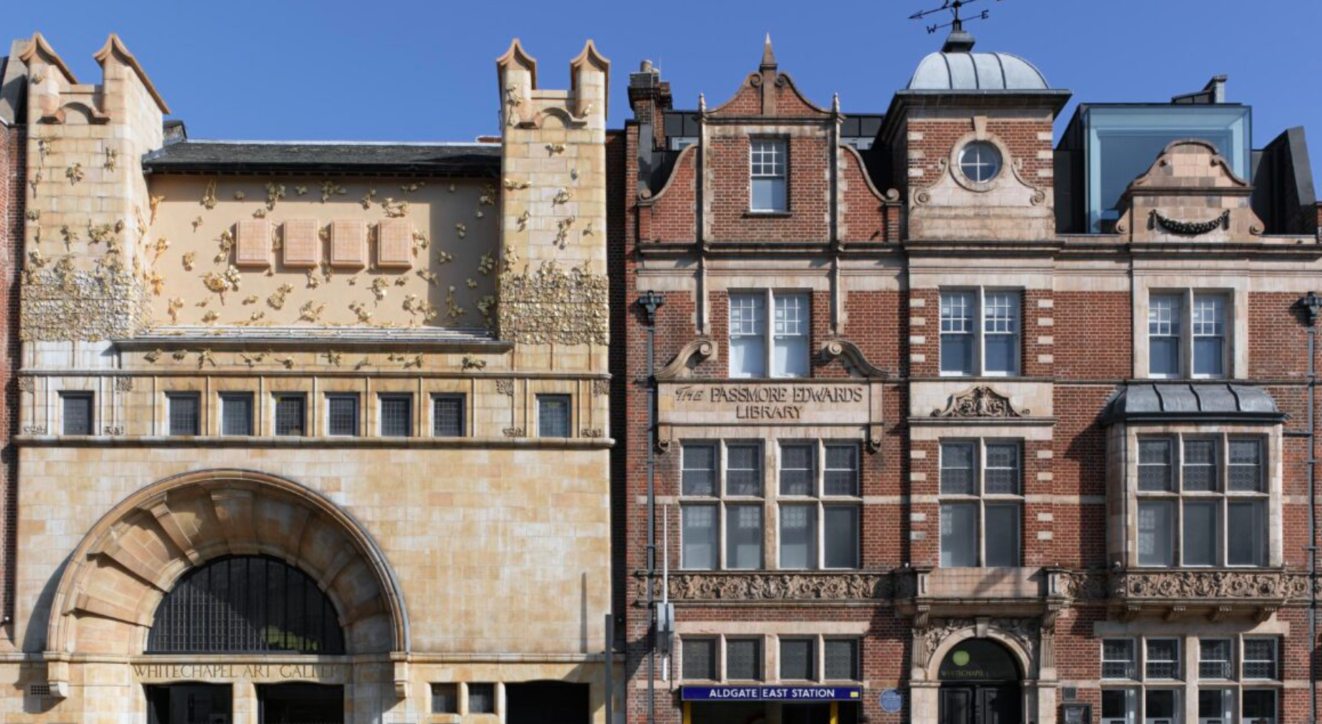 Street view of two historic buildings, one is the Whitechapel Art Gallery and the other is the Passmore Edwards Library, with clear blue sky above and a blue sign for Aldgate East Station at the bottom.