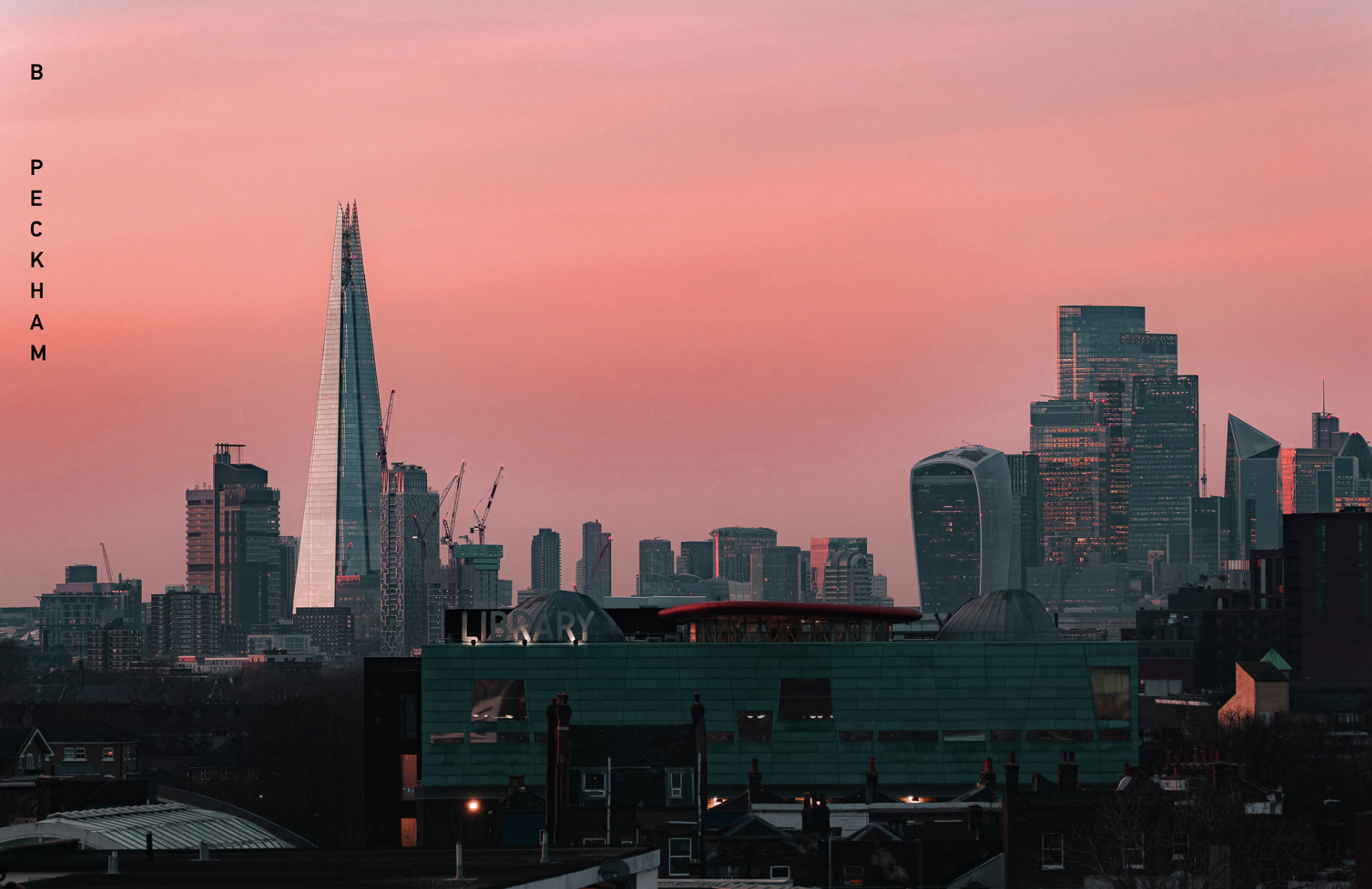City skyline during sunset featuring tall skyscrapers, including The Shard, London, with pinkish sky in the background, and the BBC library building visible in the foreground.