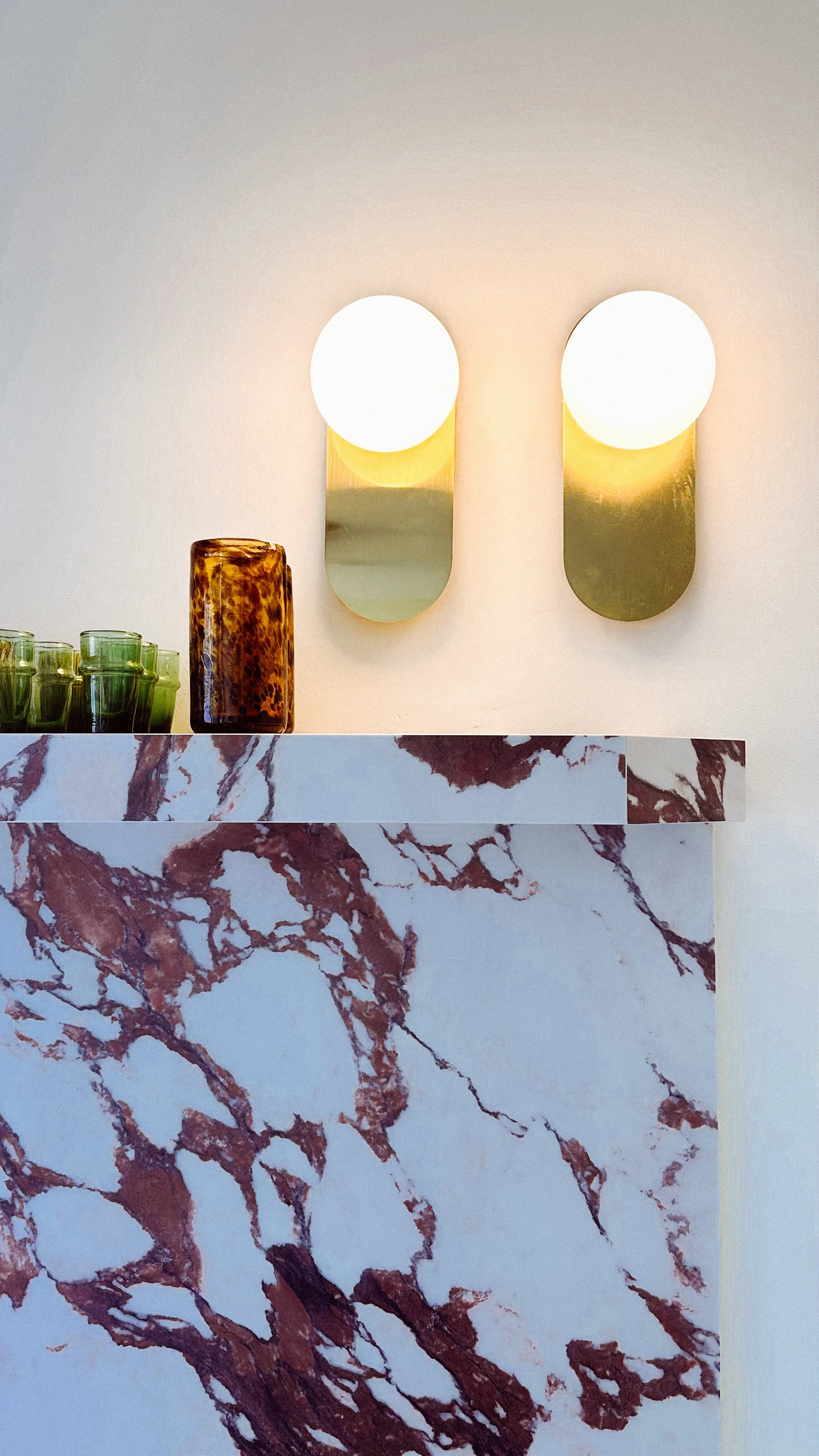 Murooj Al Furjan custom bar counter with marble finish, brass wall lights and decorative glassware.