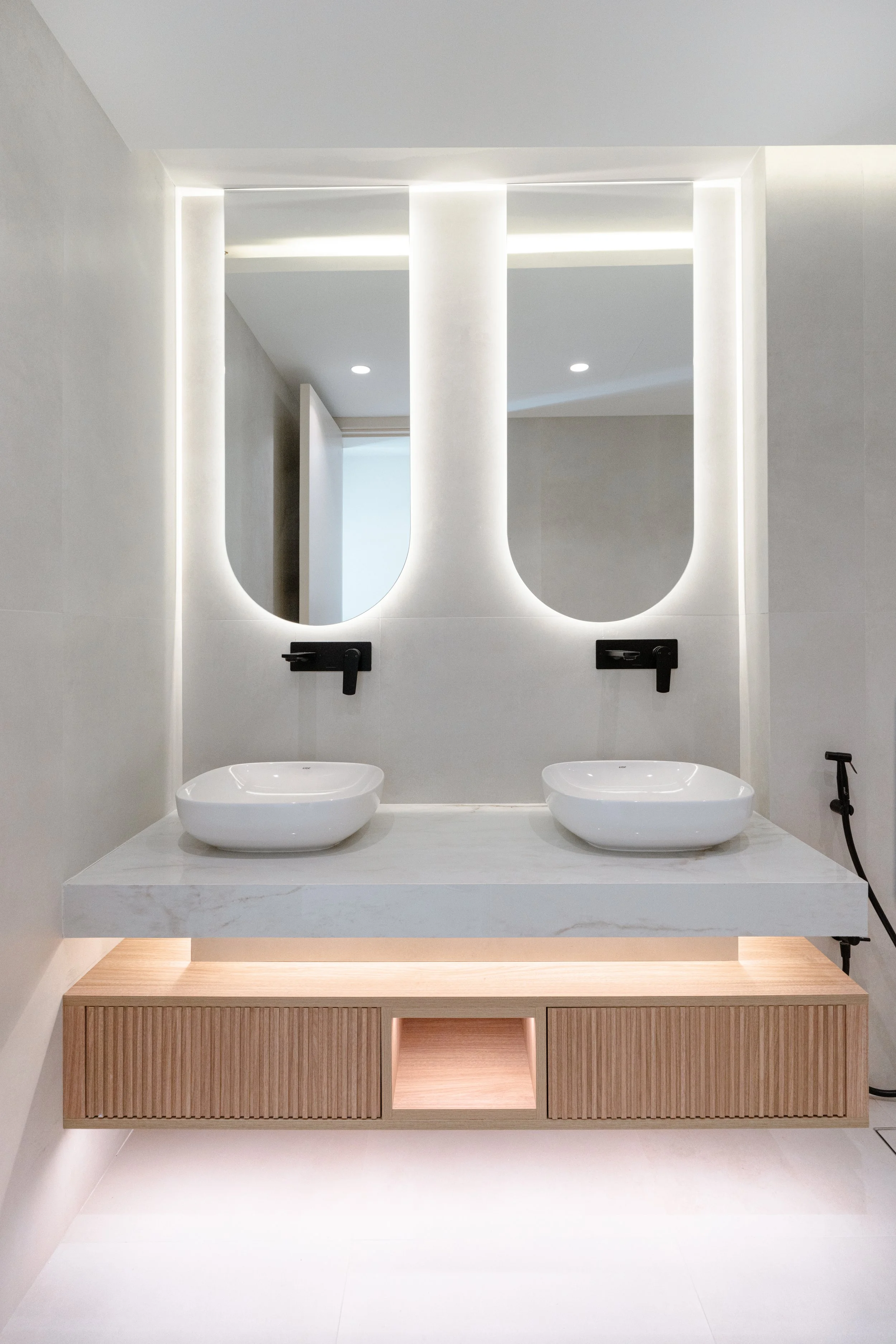 Double bathroom vanity with custom timber drawers, backlit mirrors and marble countertop.