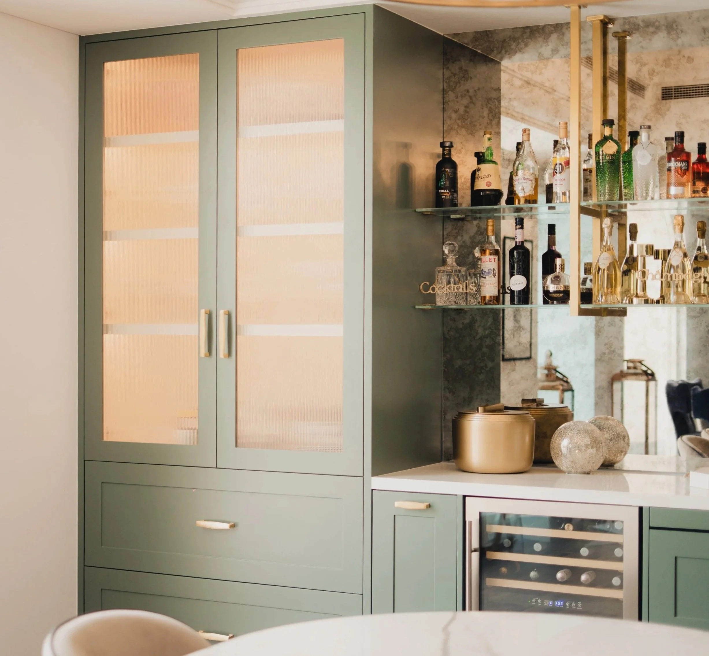 Custom green kitchen cabinetry with glass-front storage and integrated lighting