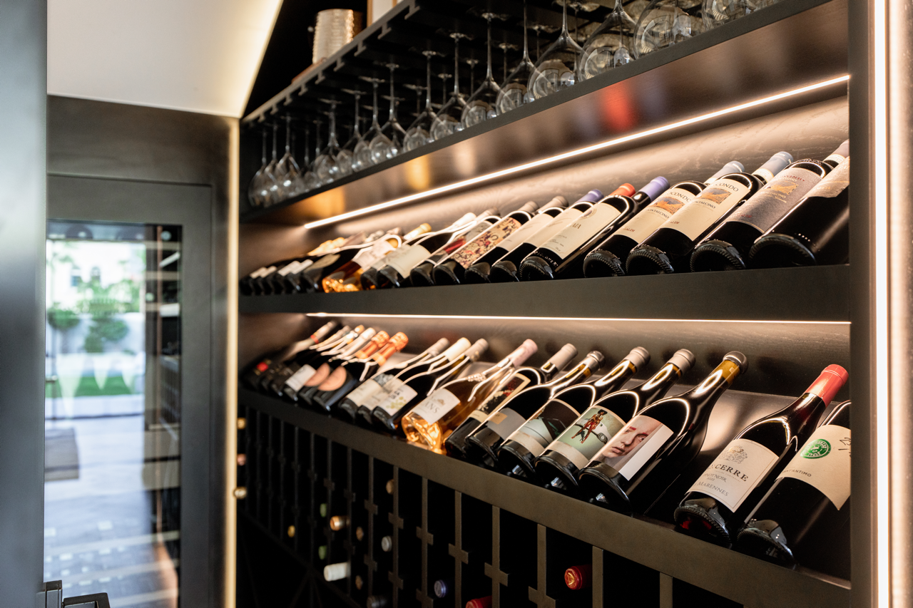 Custom wine storage joinery with illuminated bottle racks and glass shelving