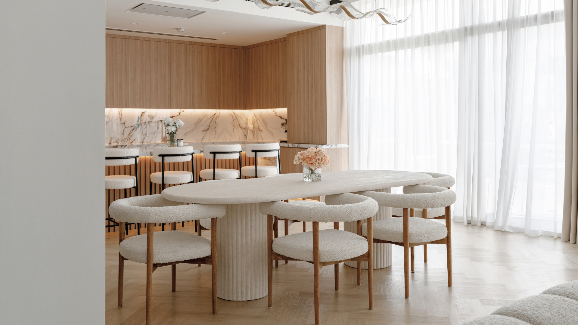 Open-plan dining area with bespoke wood kitchen and marble island in a Tilal Al Furjan villa.