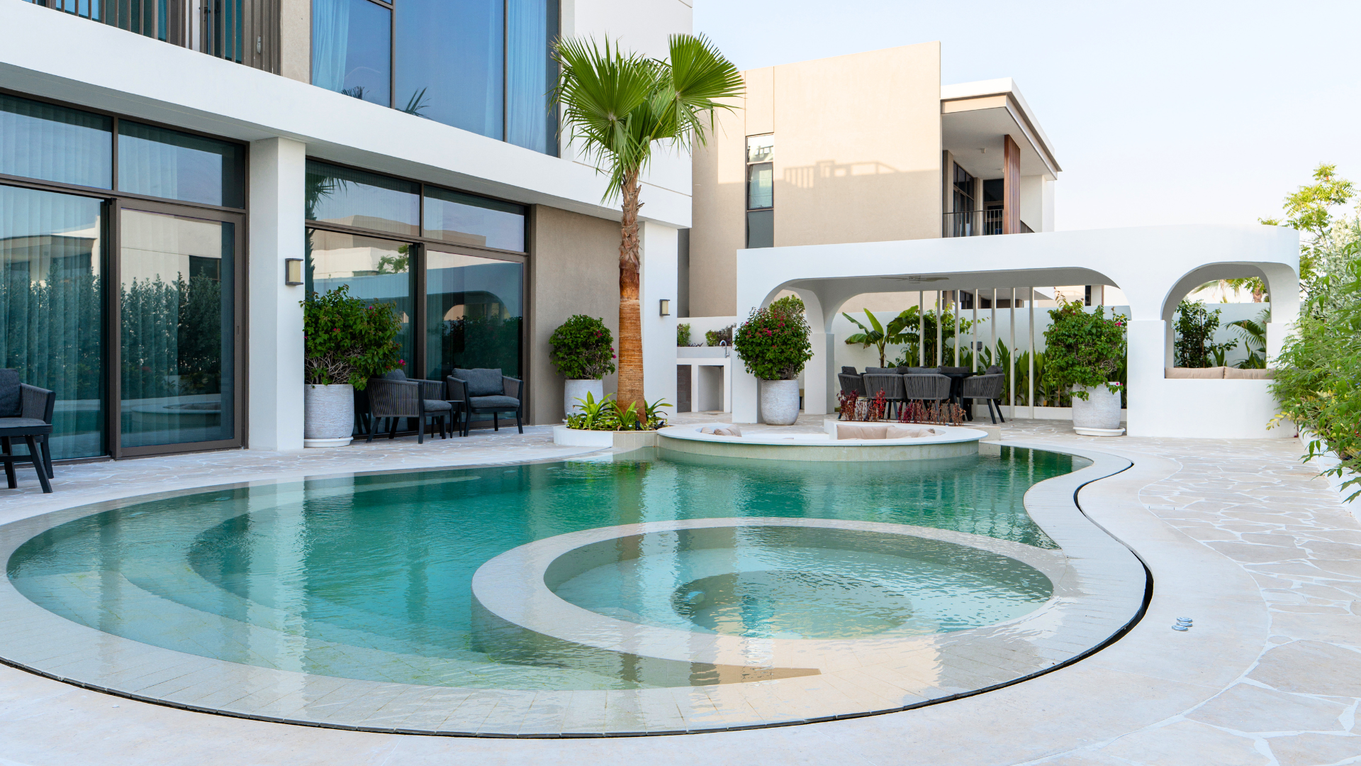 Organic swimming pool with integrated circular spa and landscaped garden at a Tilal Al Furjan villa in Dubai.
