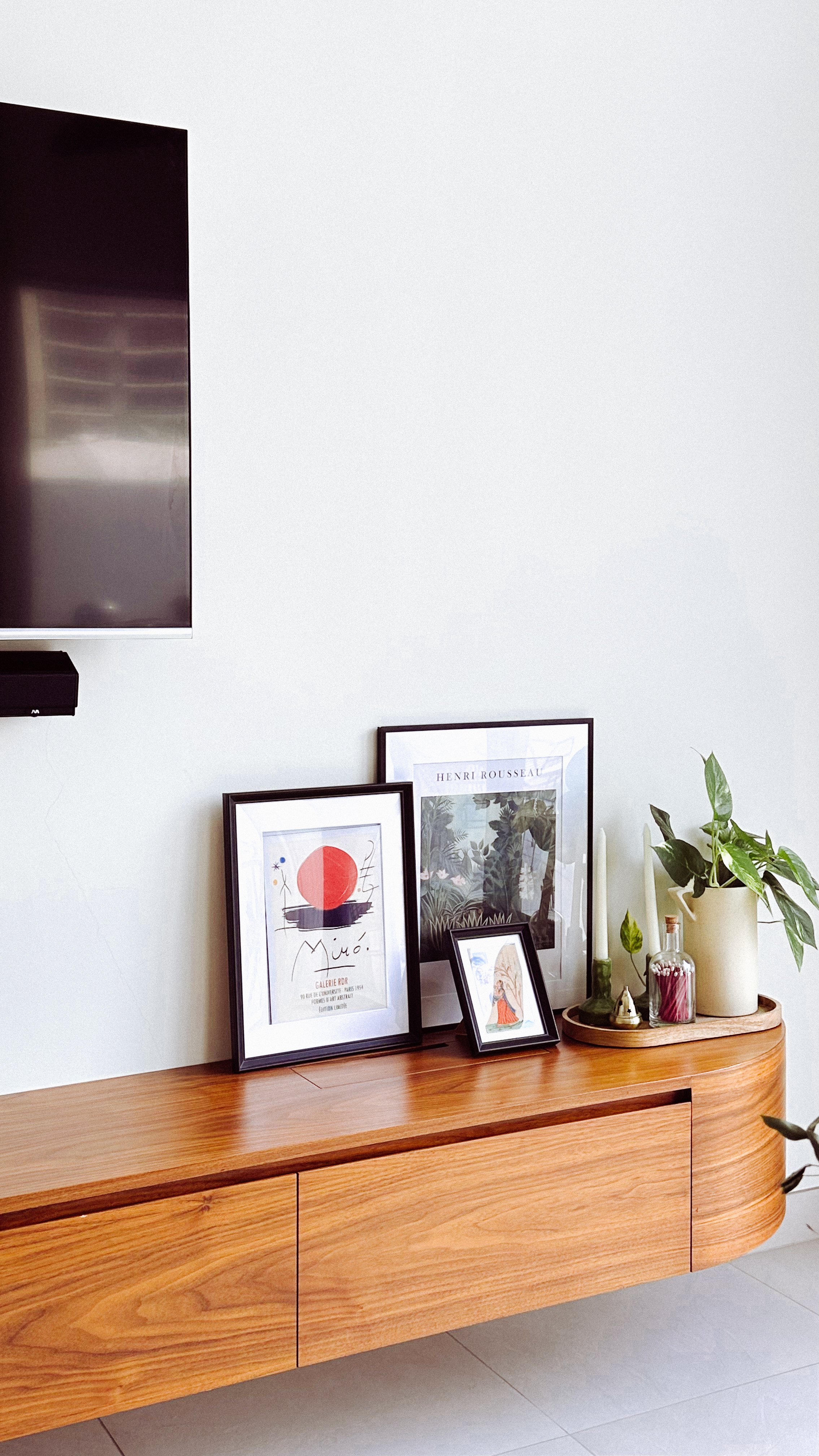 Murooj Al Furjan villa interior with wooden console, framed artwork, indoor plant and decorative styling.