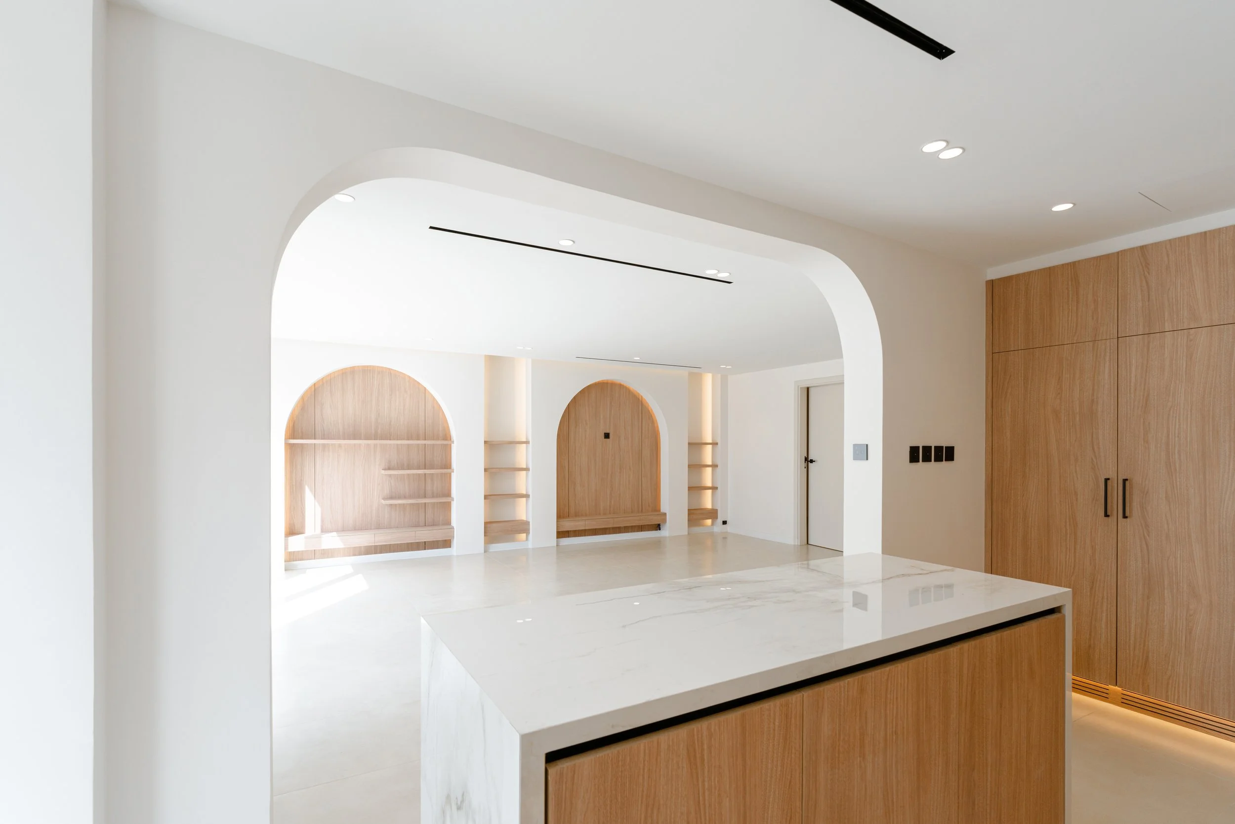 Bright villa kitchen with timber cabinetry, white island and arched architectural details.