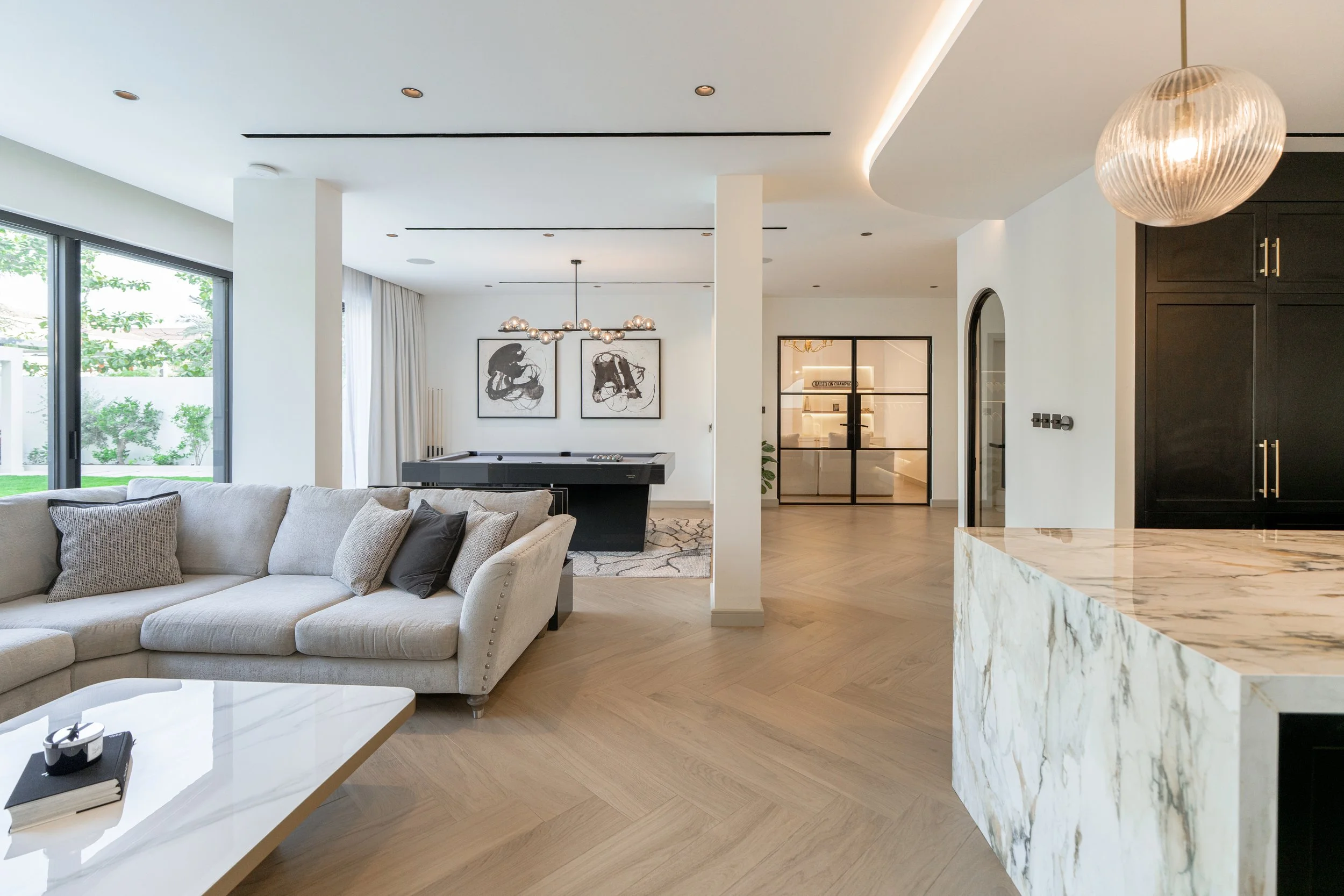Open-plan Jumeirah Park villa living and kitchen area with marble finishes, pool table and garden access.