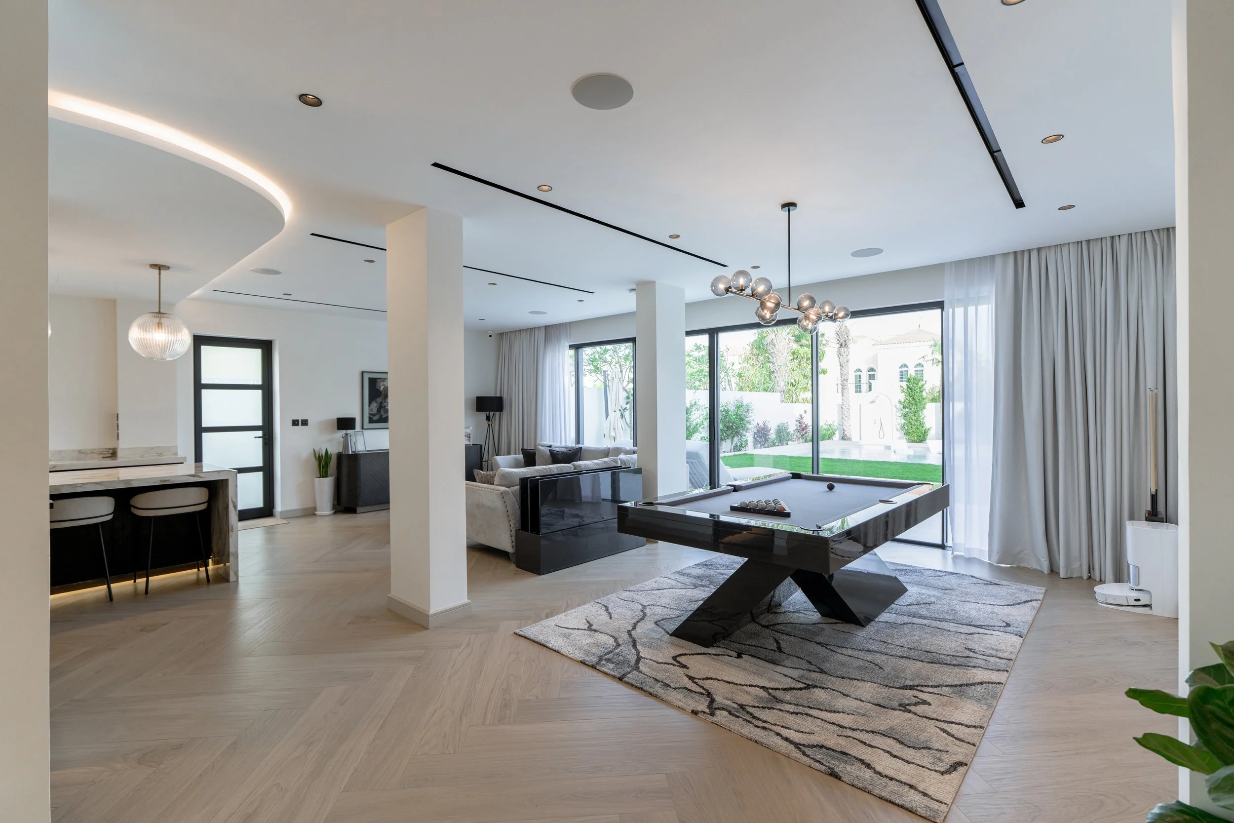 Open-plan renovated villa living room with neutral finishes, statement lighting and garden views.
