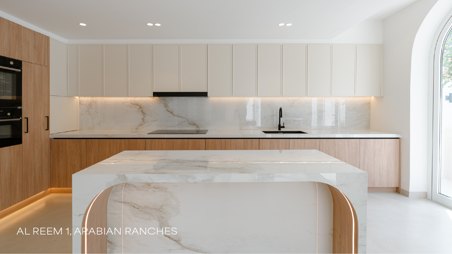 Luxury villa kitchen in Al Reem 1, Arabian Ranches with island, cabinetry and arched window.
