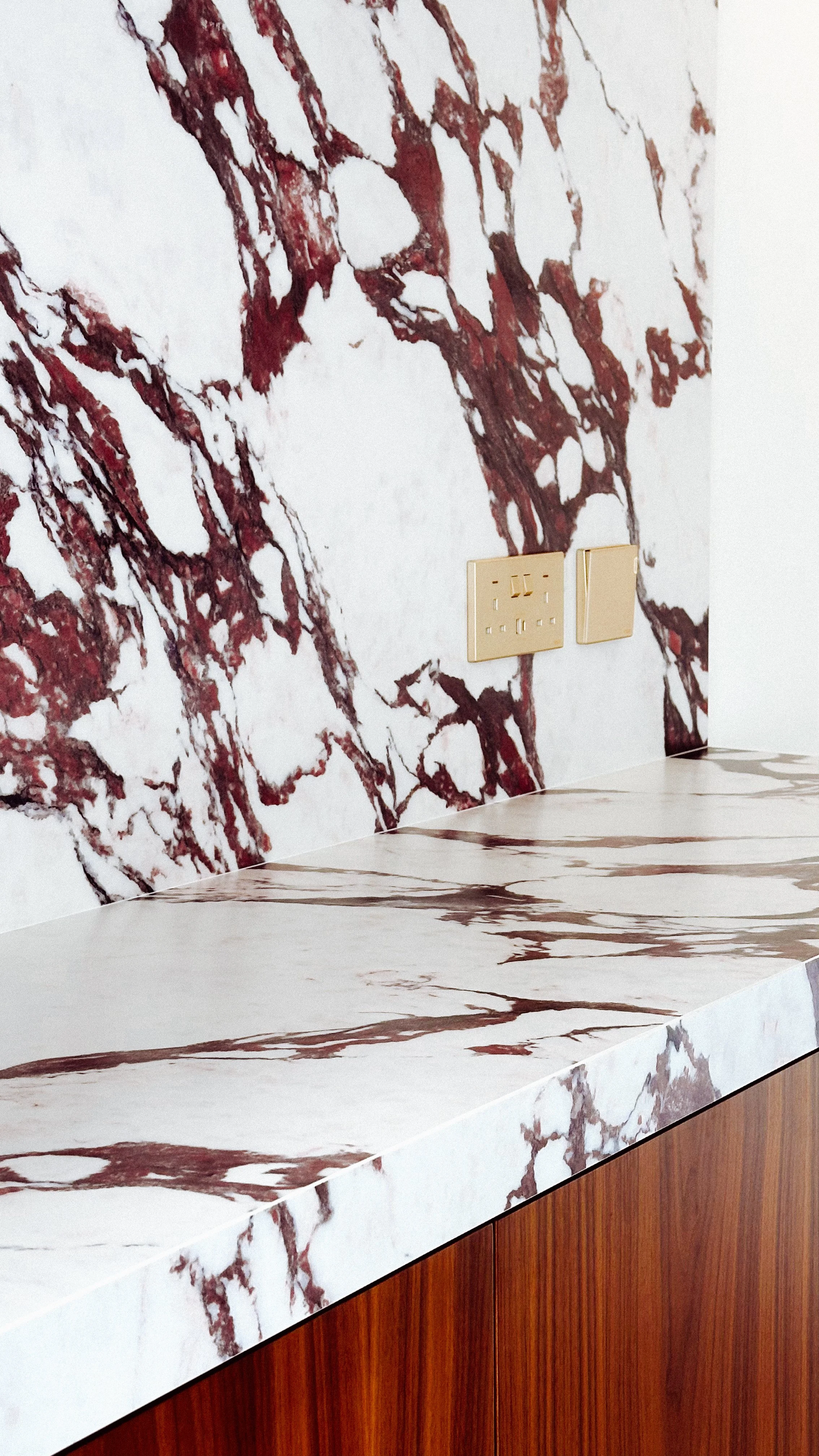 Close-up of bespoke marble bar counter and backsplash with brass switches in a Murooj Al Furjan villa.