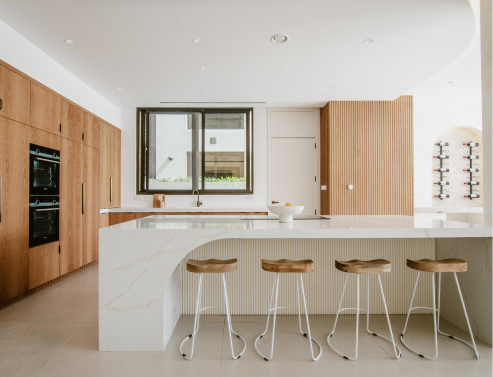 Renovated villa kitchen with white island, timber cabinetry and bar seating