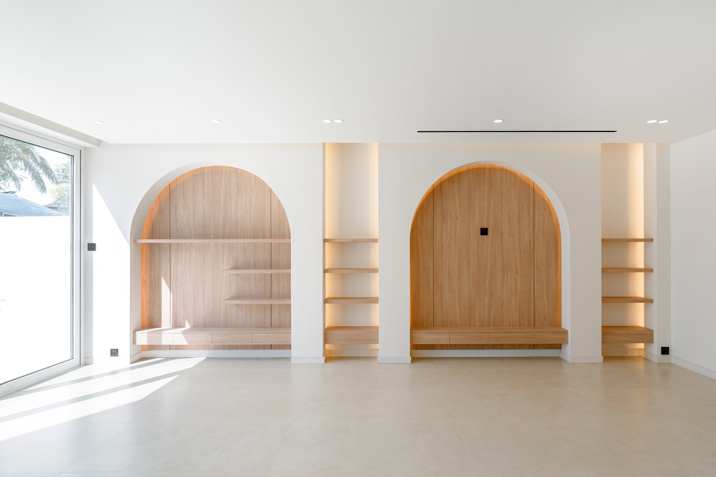 Al Reem 1 villa interior with arched custom joinery, built-in shelving and warm timber feature wall.