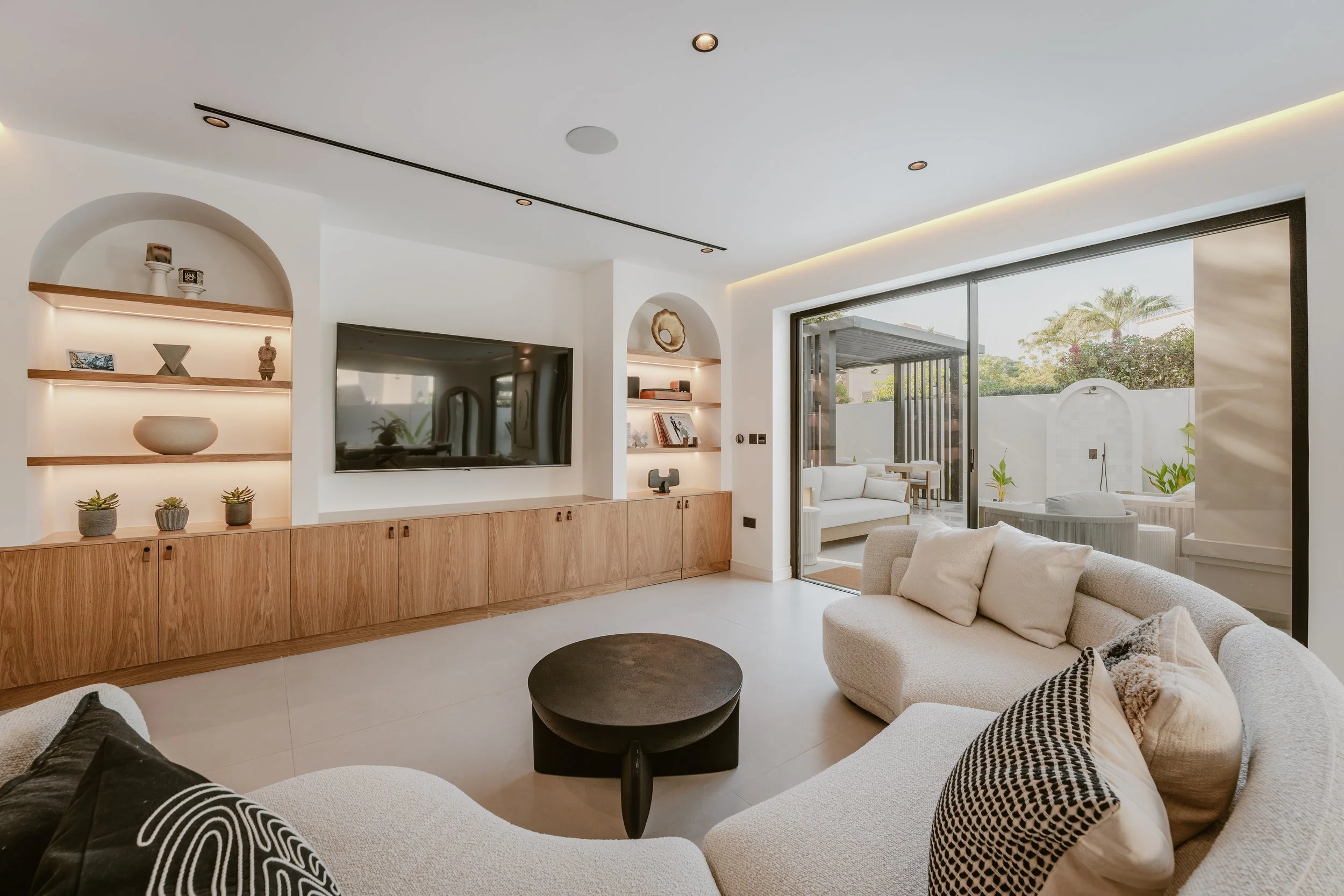 Renovated villa living room with custom media wall, garden access and neutral interior finishes.