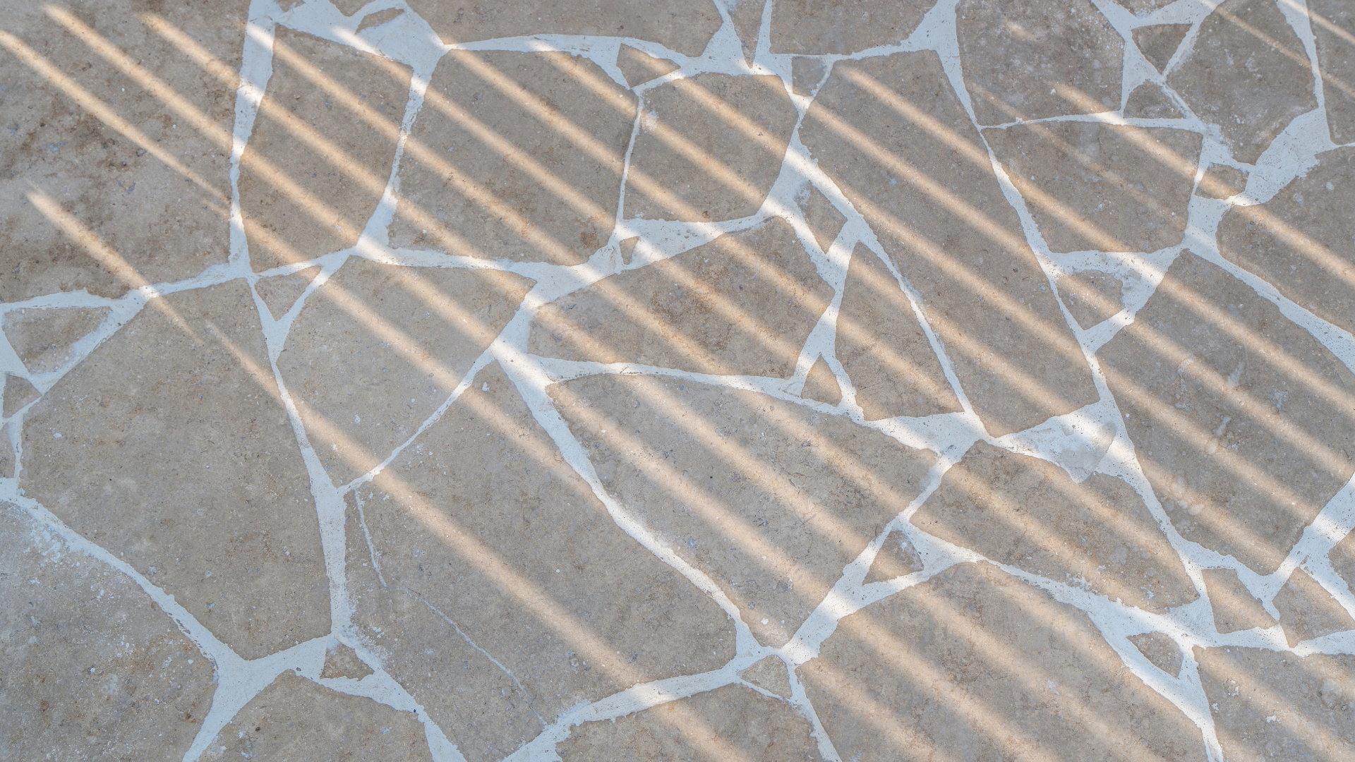 Natural crazy paving with irregular stonework and pergola shadows in a landscaped Dubai villa garden.