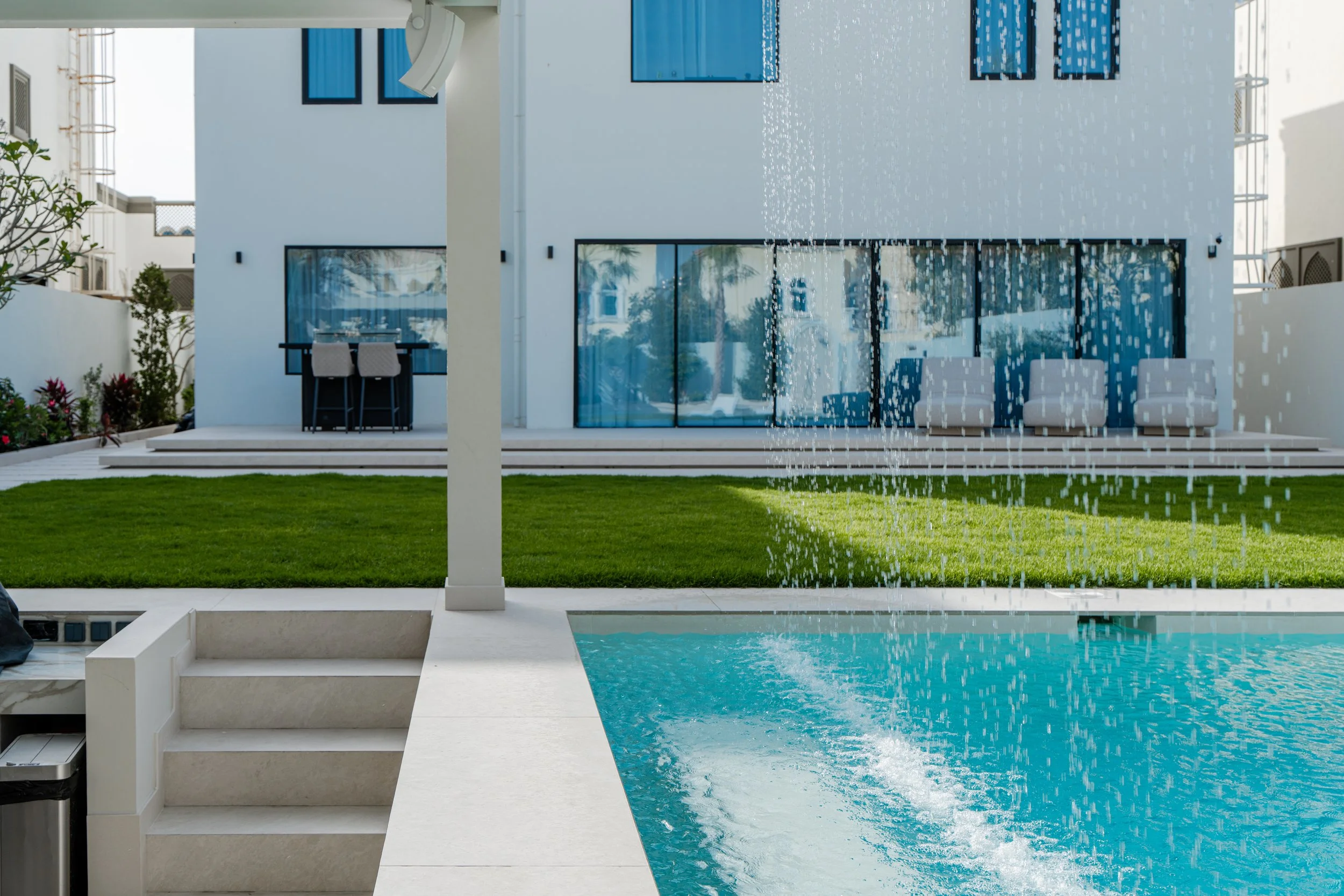 Jumeirah Park villa garden with swimming pool, lawn, water feature and outdoor terrace.