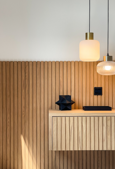 Custom fluted wood media wall with integrated storage and pendant lighting