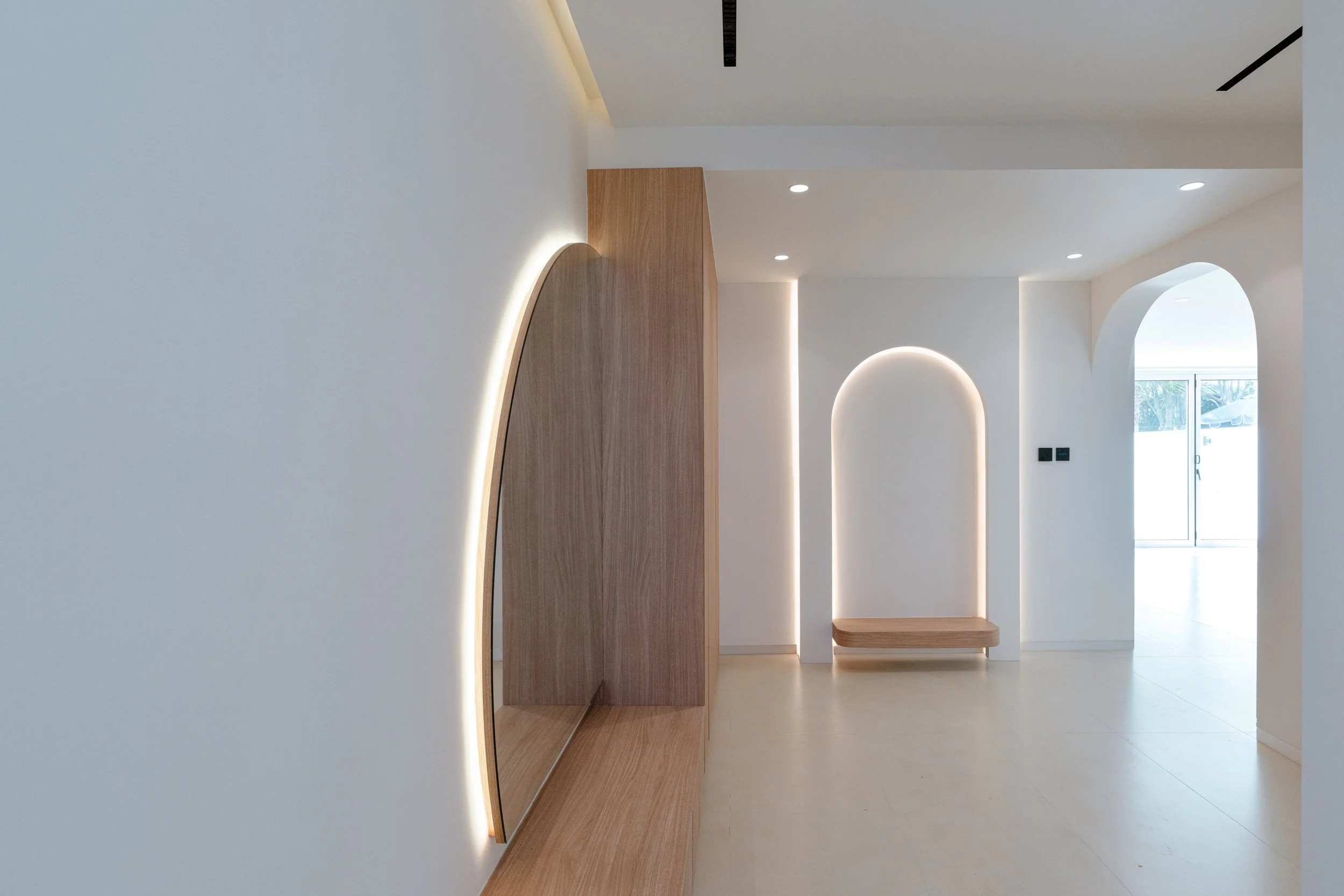Al Reem 1 villa entrance with curved timber feature wall, integrated lighting and arched interior detail.
