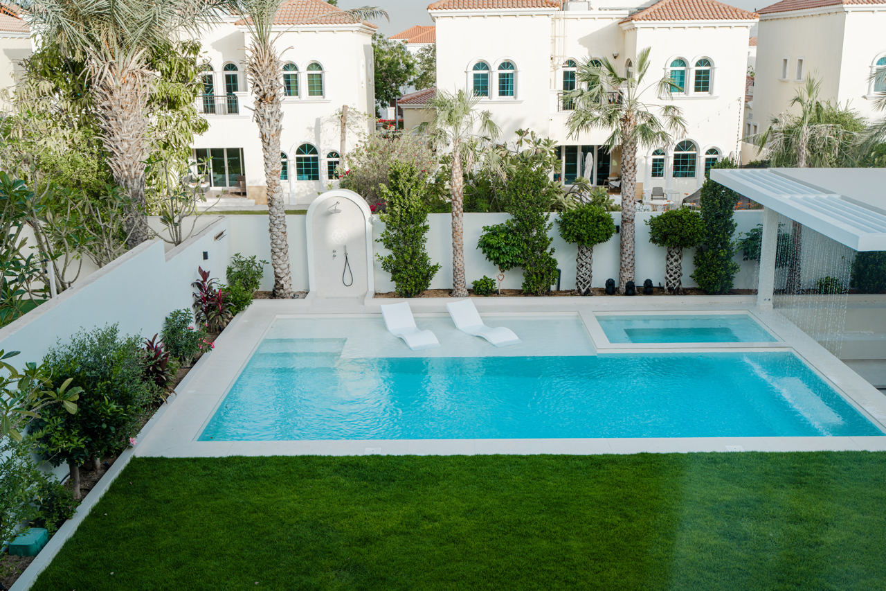 Dubai villa garden with swimming pool, lawn, landscaping and outdoor seating area.