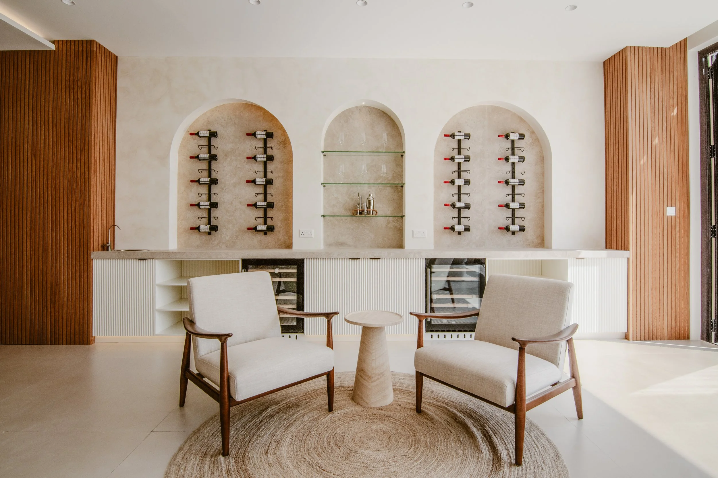 Bright villa lounge with custom wine storage, neutral seating and bespoke wall niches.