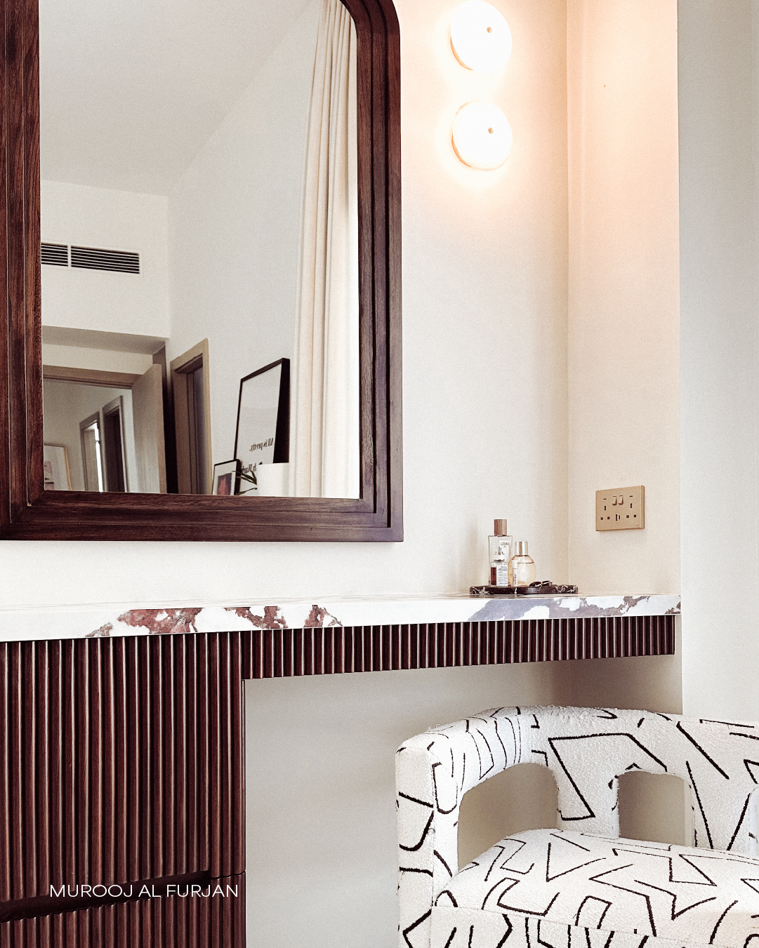 Custom vanity area in Murooj Al Furjan with fluted timber detailing, marble counter, wall mirror and accent chair