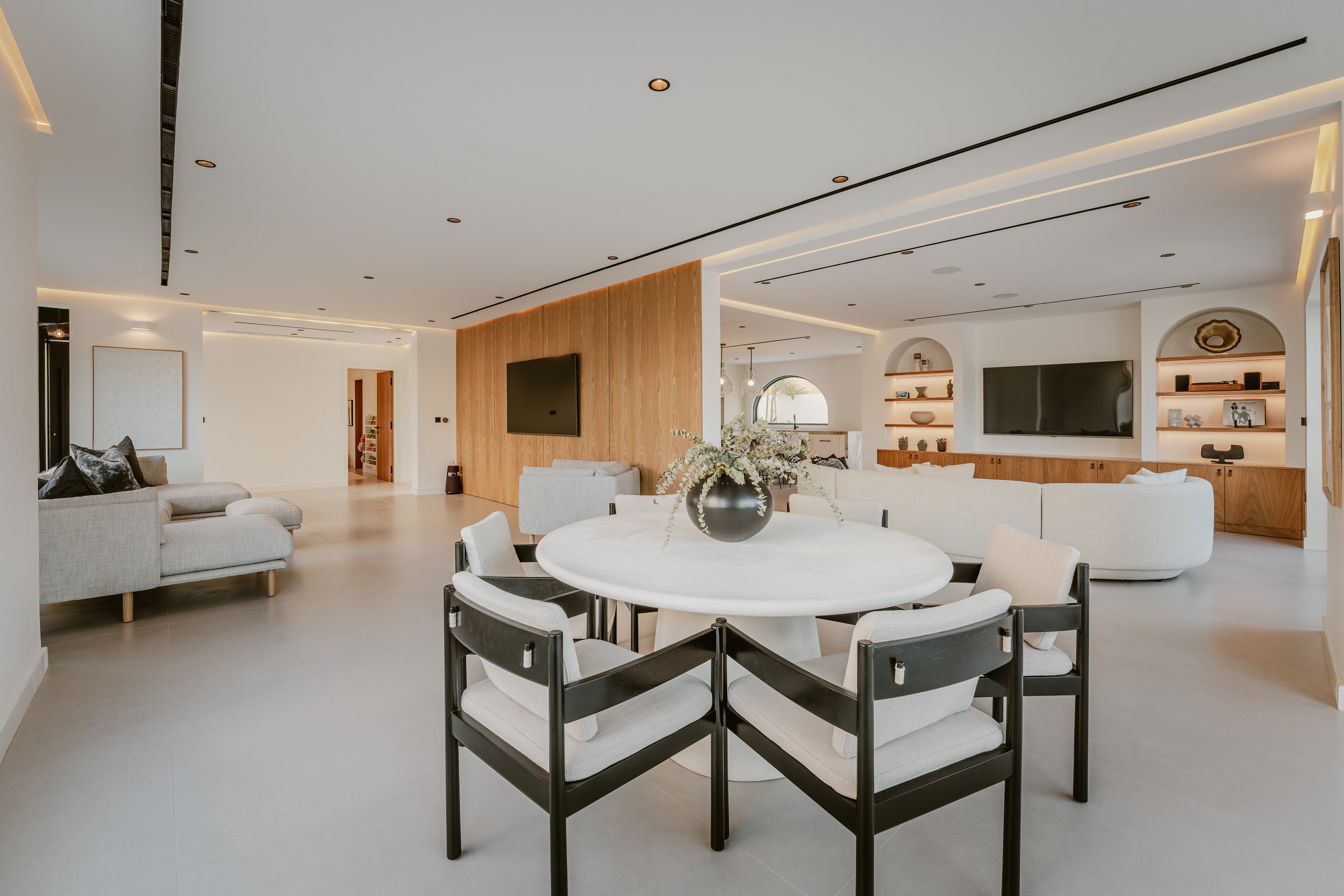 Open-plan Al Mahra villa dining and living area with round dining table, pendant lighting and custom wall finishes.